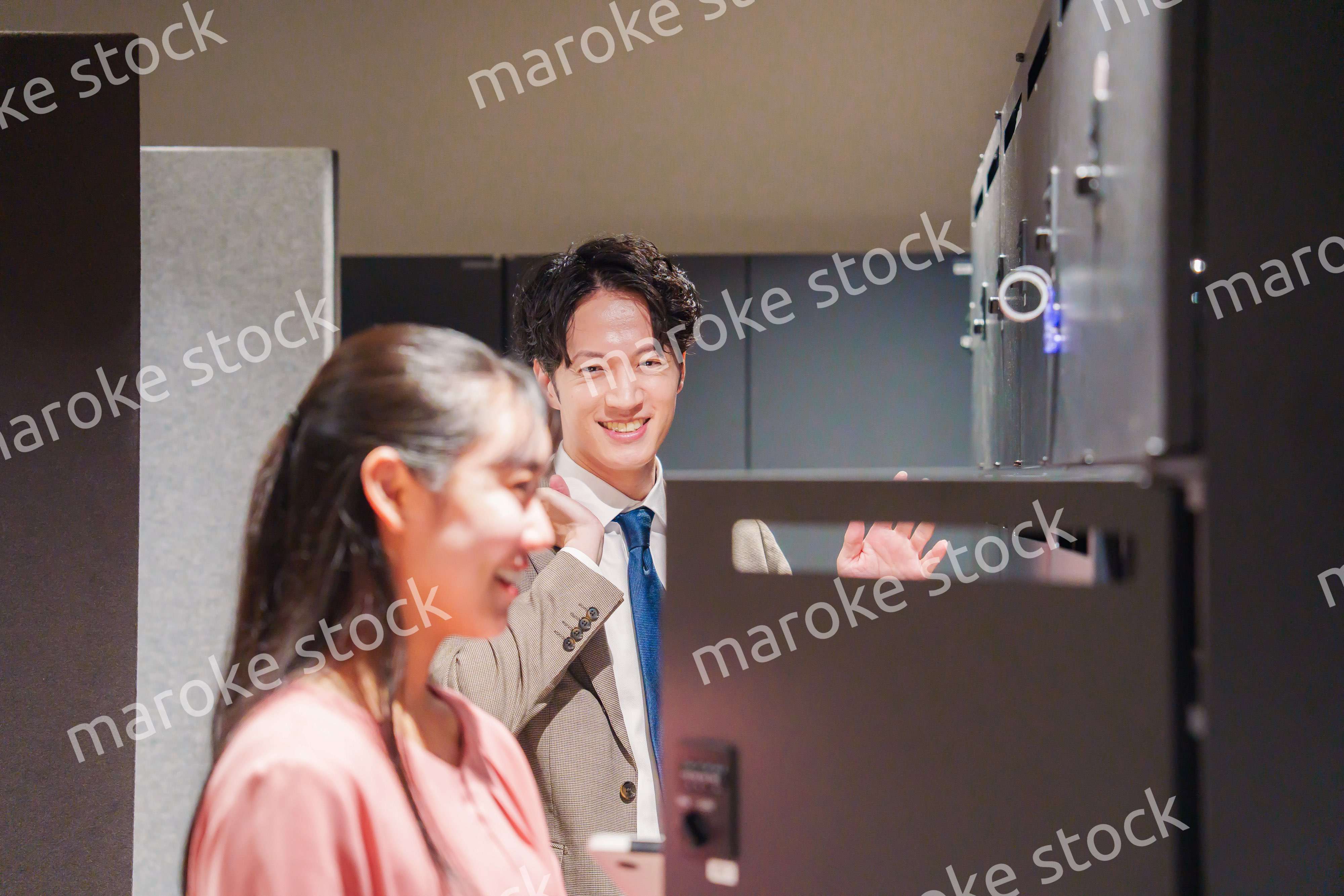 オフィスのロッカーで会話をする男女の会社員