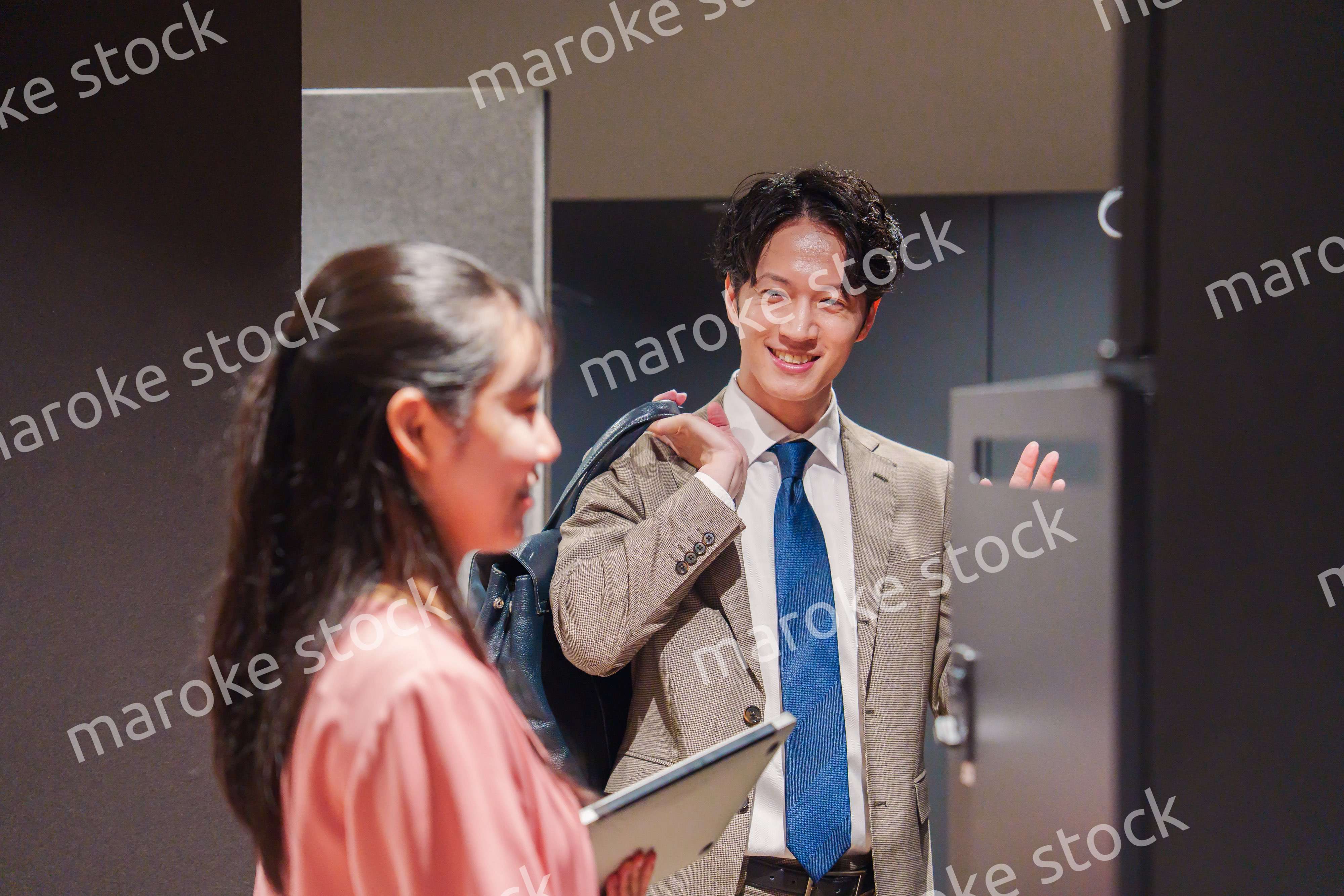 オフィスのロッカーで会話をする男女の会社員