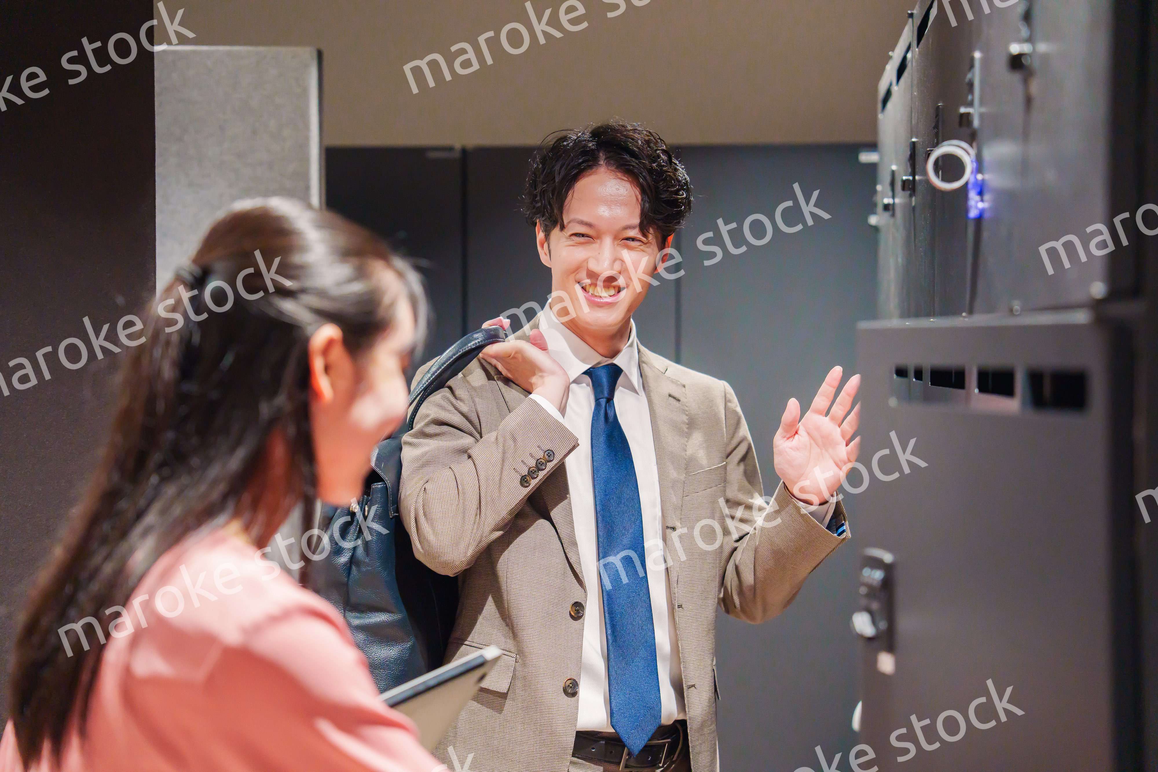 オフィスのロッカーで会話をする男女の会社員