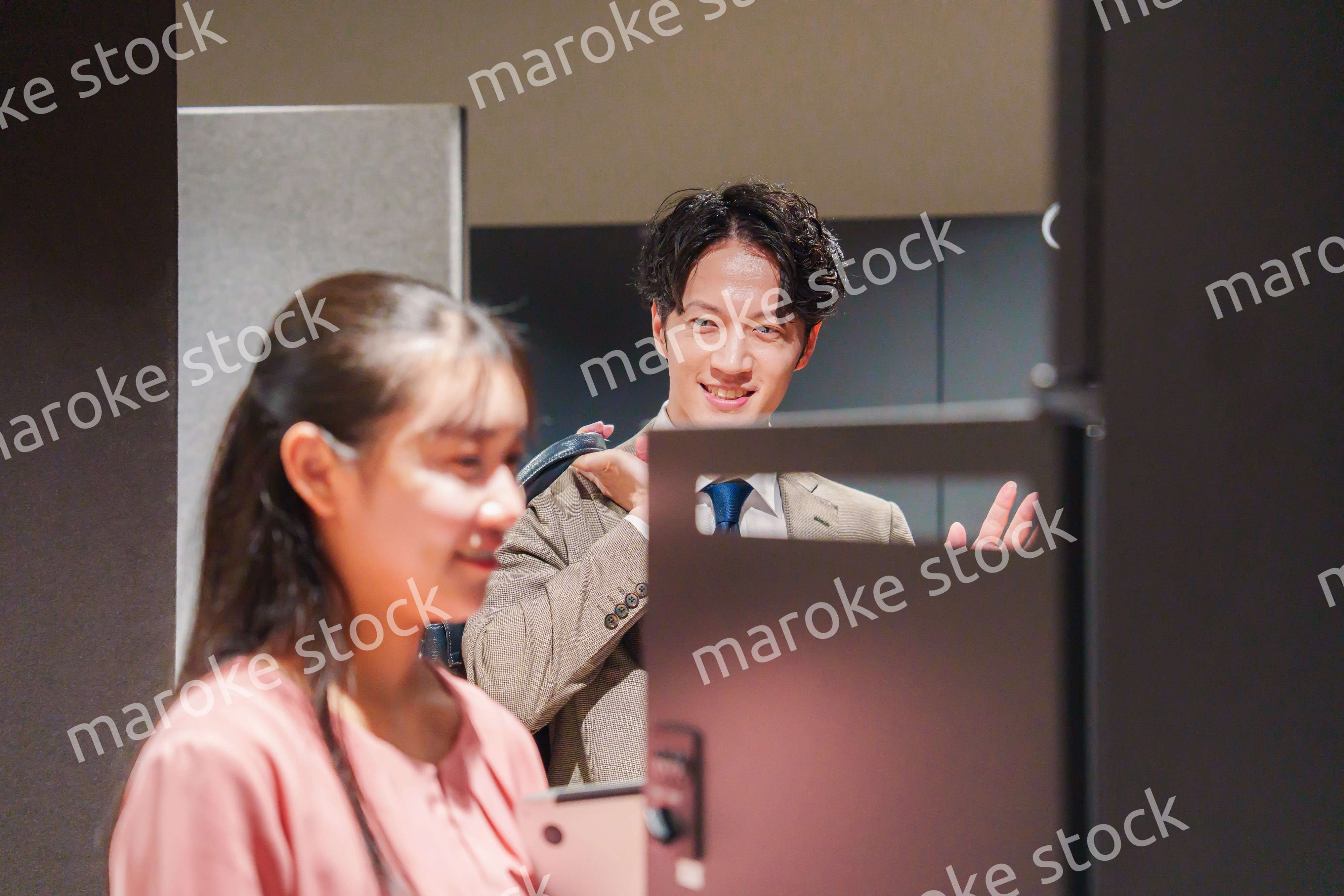 オフィスのロッカーで会話をする男女の会社員