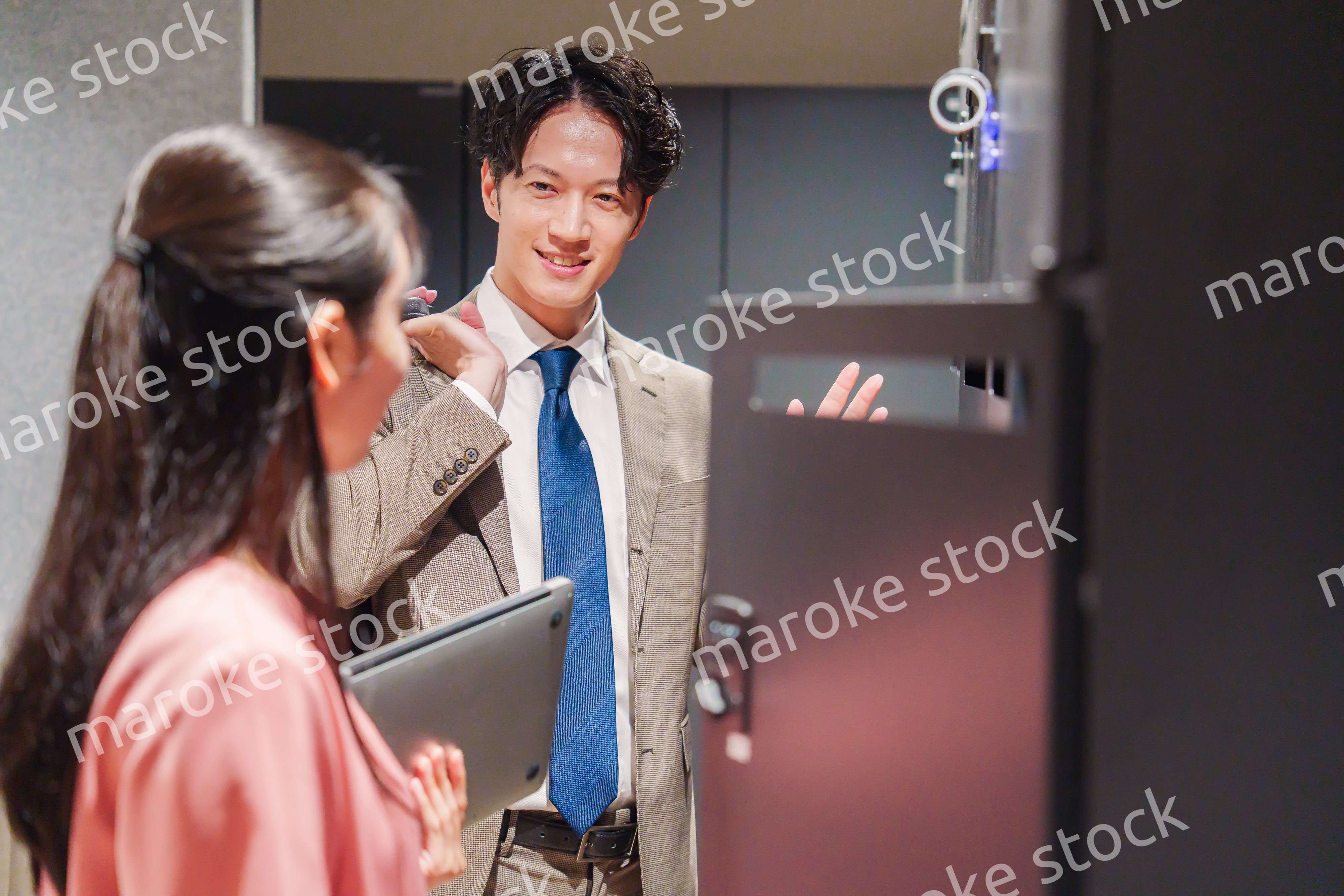 オフィスのロッカーで会話をする男女の会社員