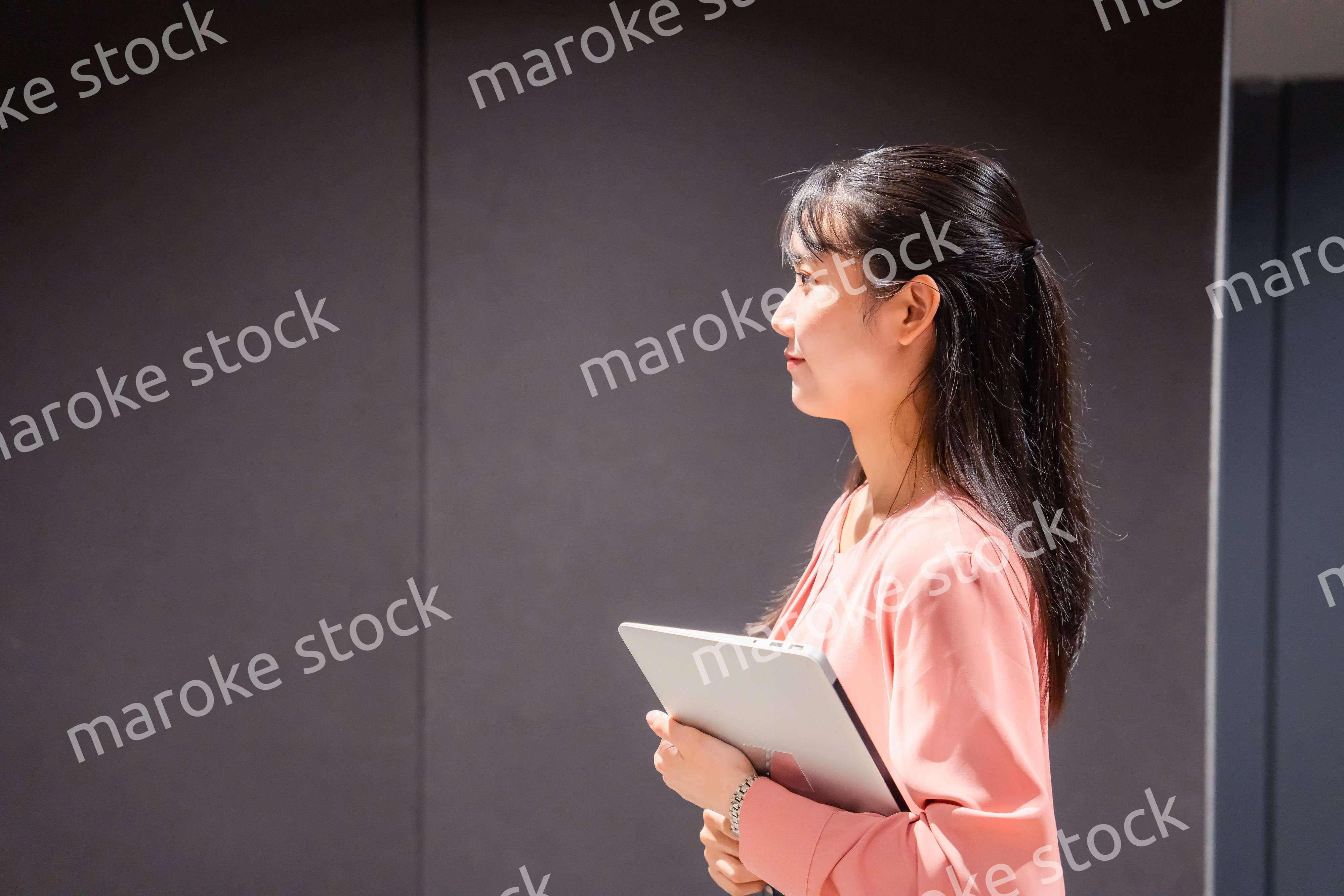 オフィスのロッカーの前でパソコンを持つ若い女性