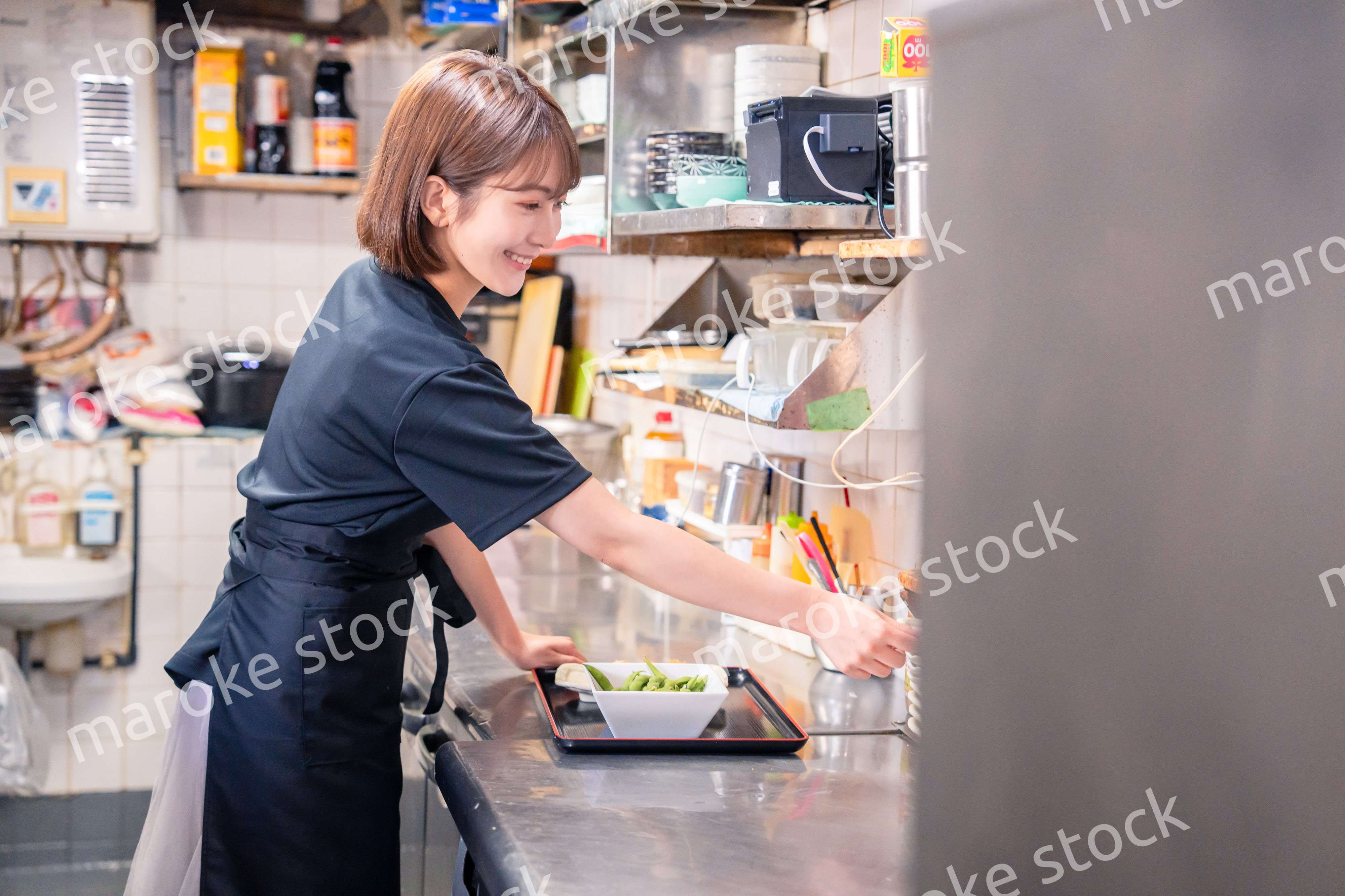 居酒屋の厨房で働くキッチンスタッフの女性