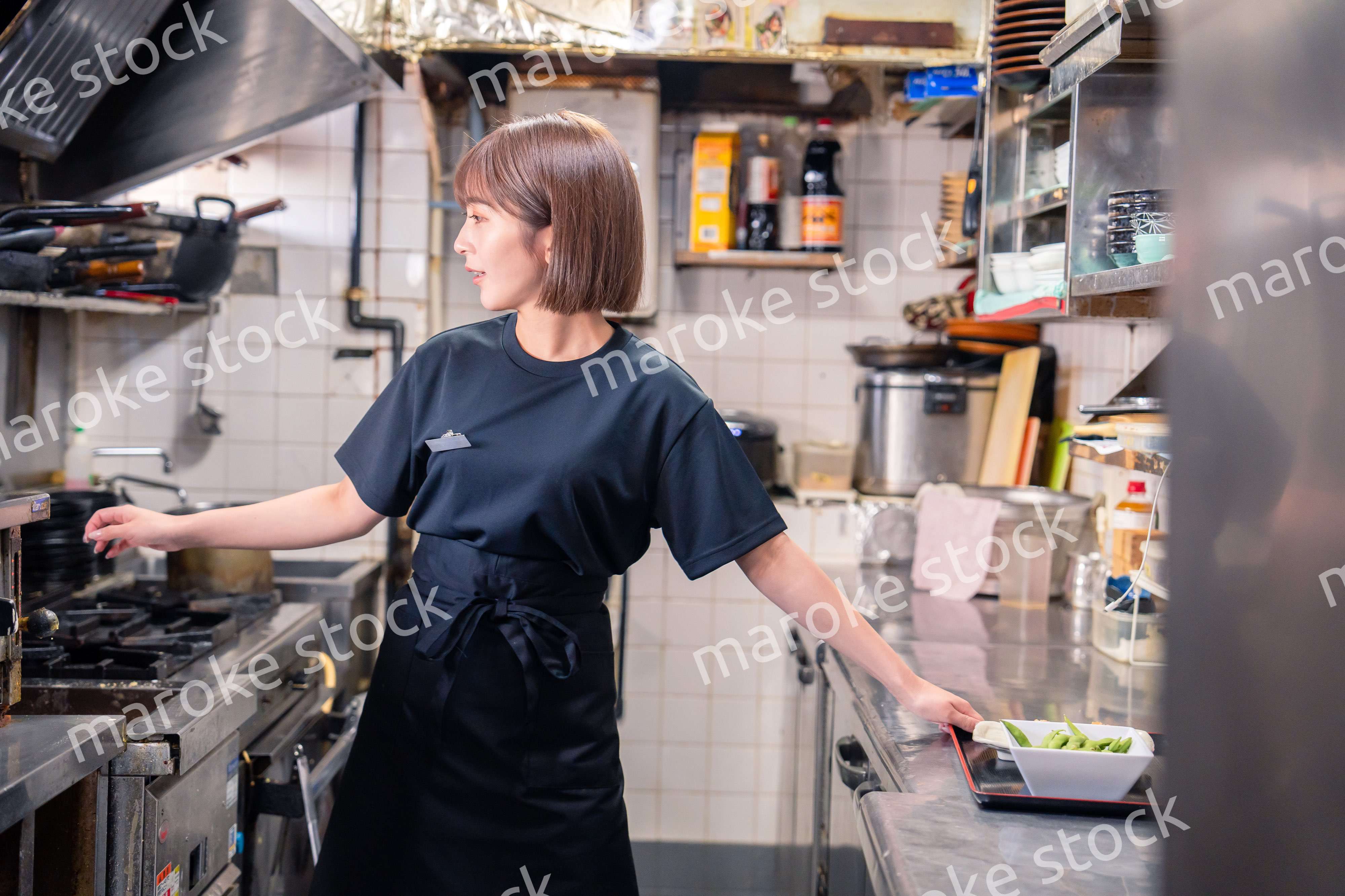 居酒屋の厨房で働くキッチンスタッフの女性