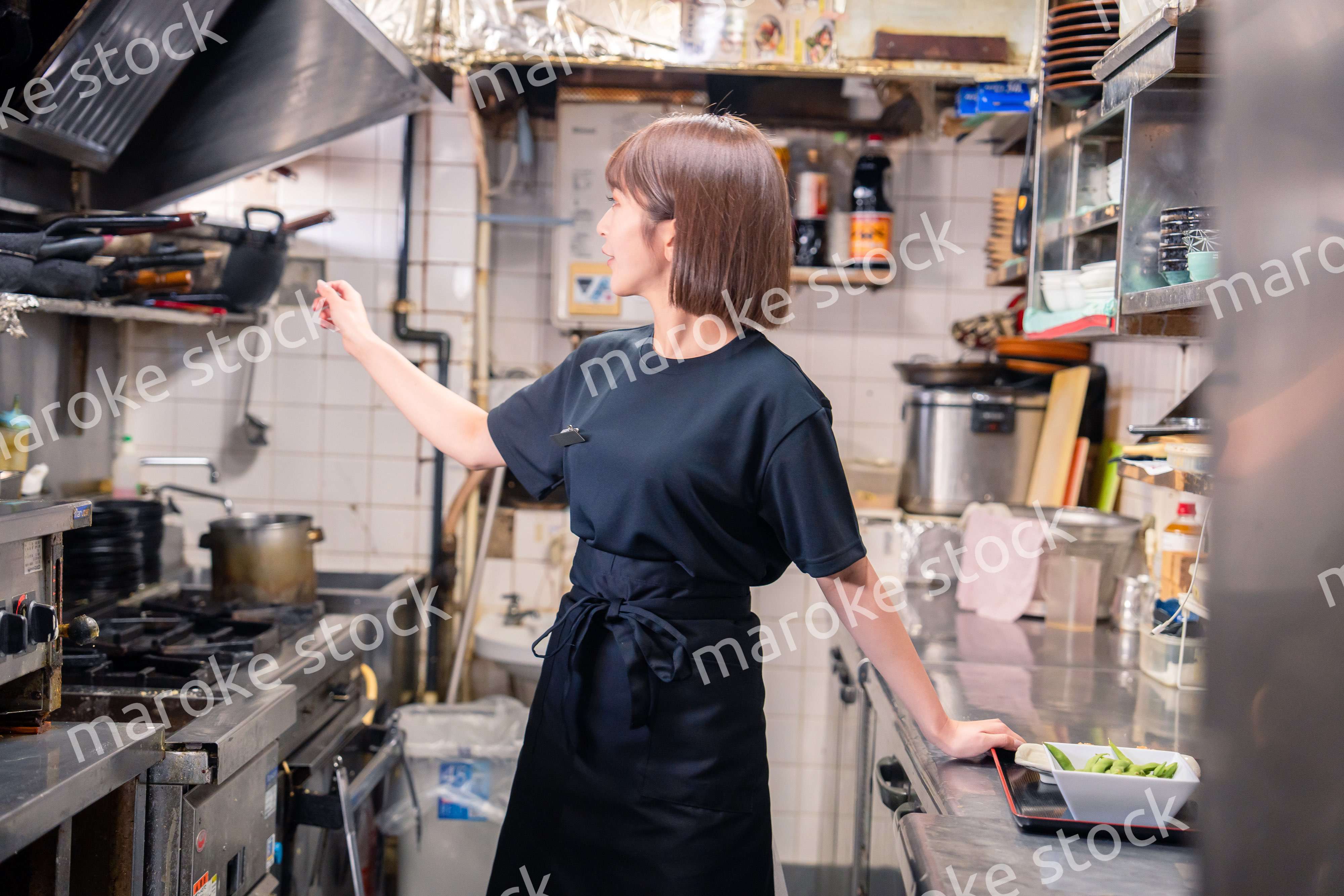 居酒屋の厨房で働くキッチンスタッフの女性