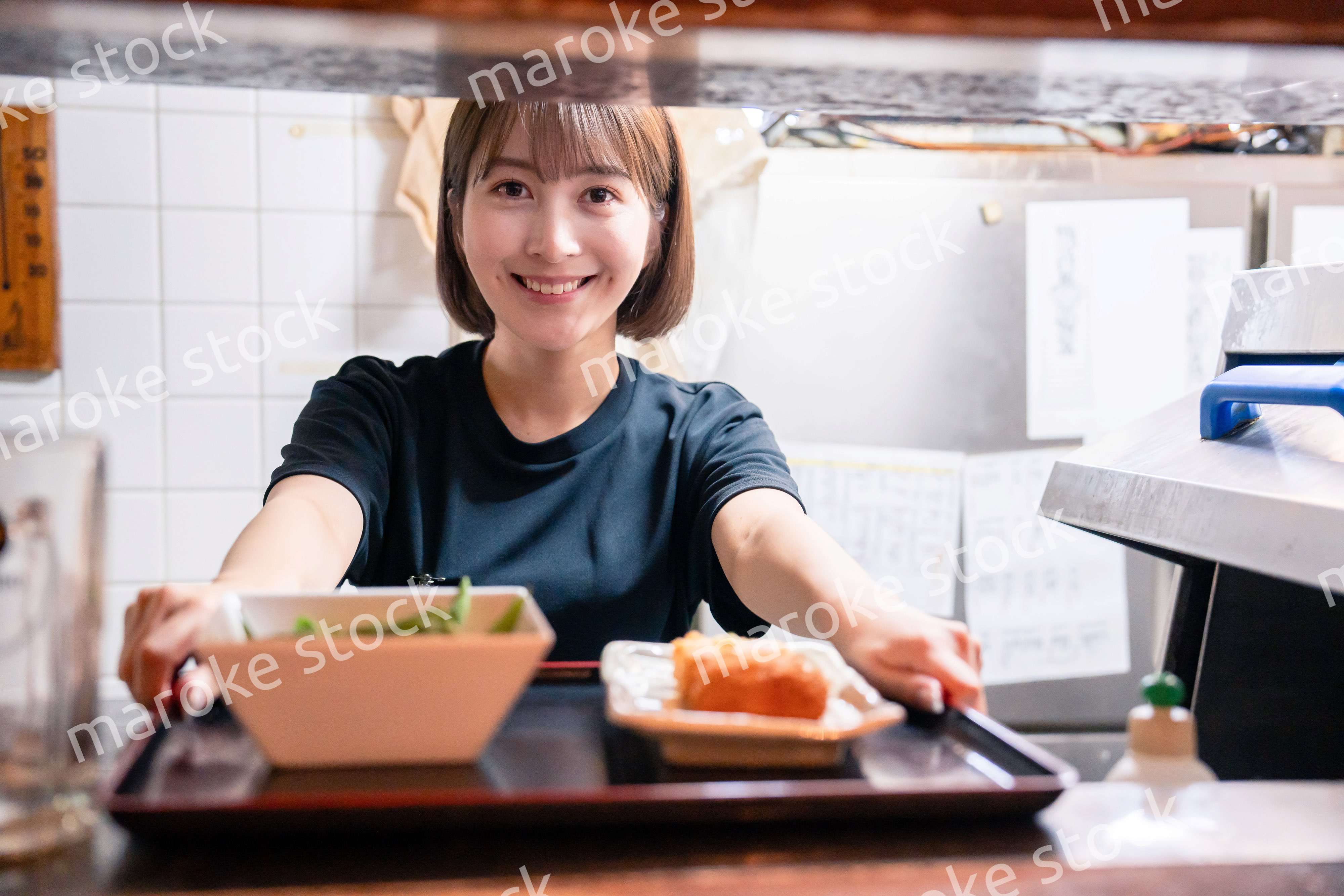 レストランでご飯を提供する若い女性のキッチンスタッフ