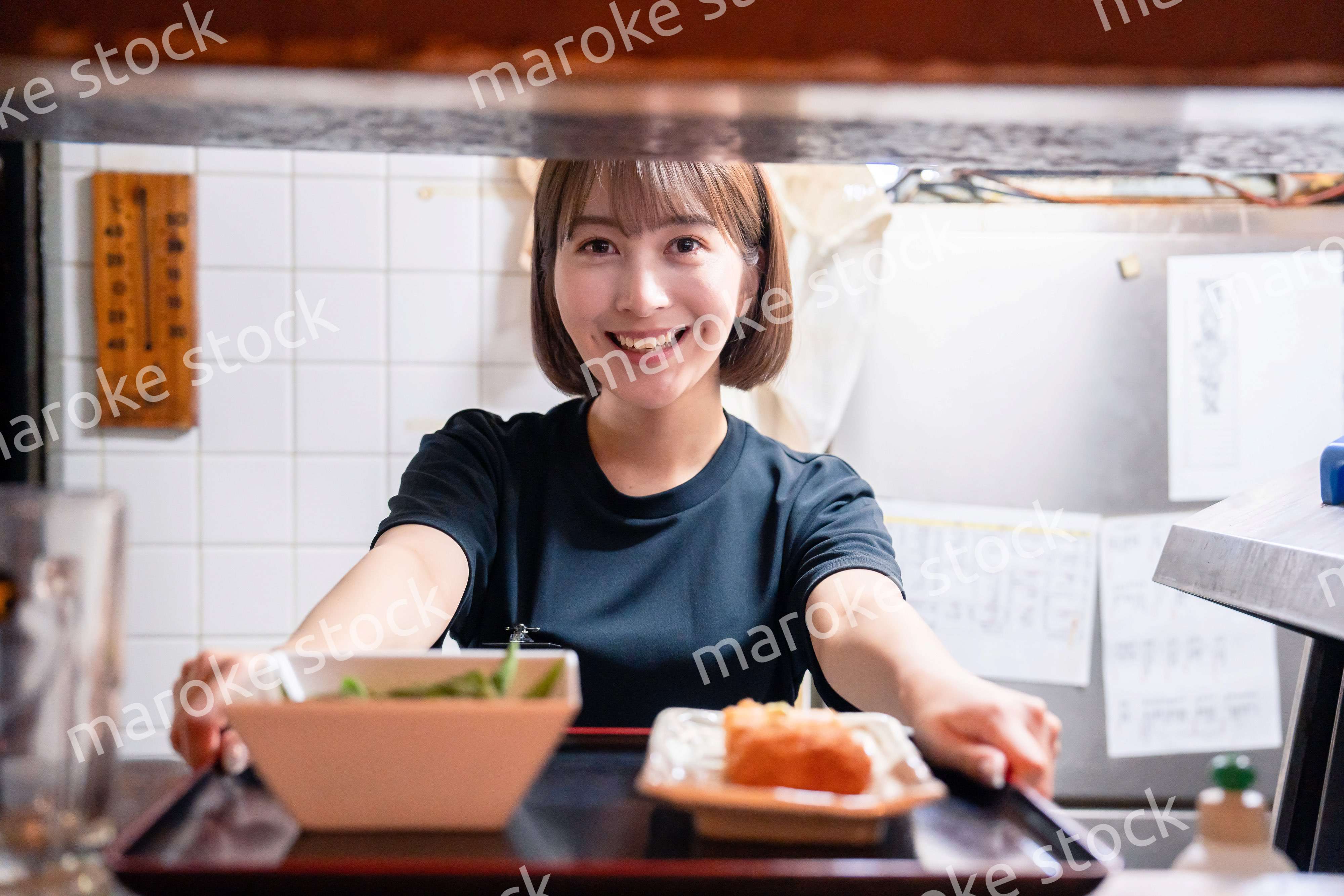 レストランでご飯を提供する若い女性のキッチンスタッフ