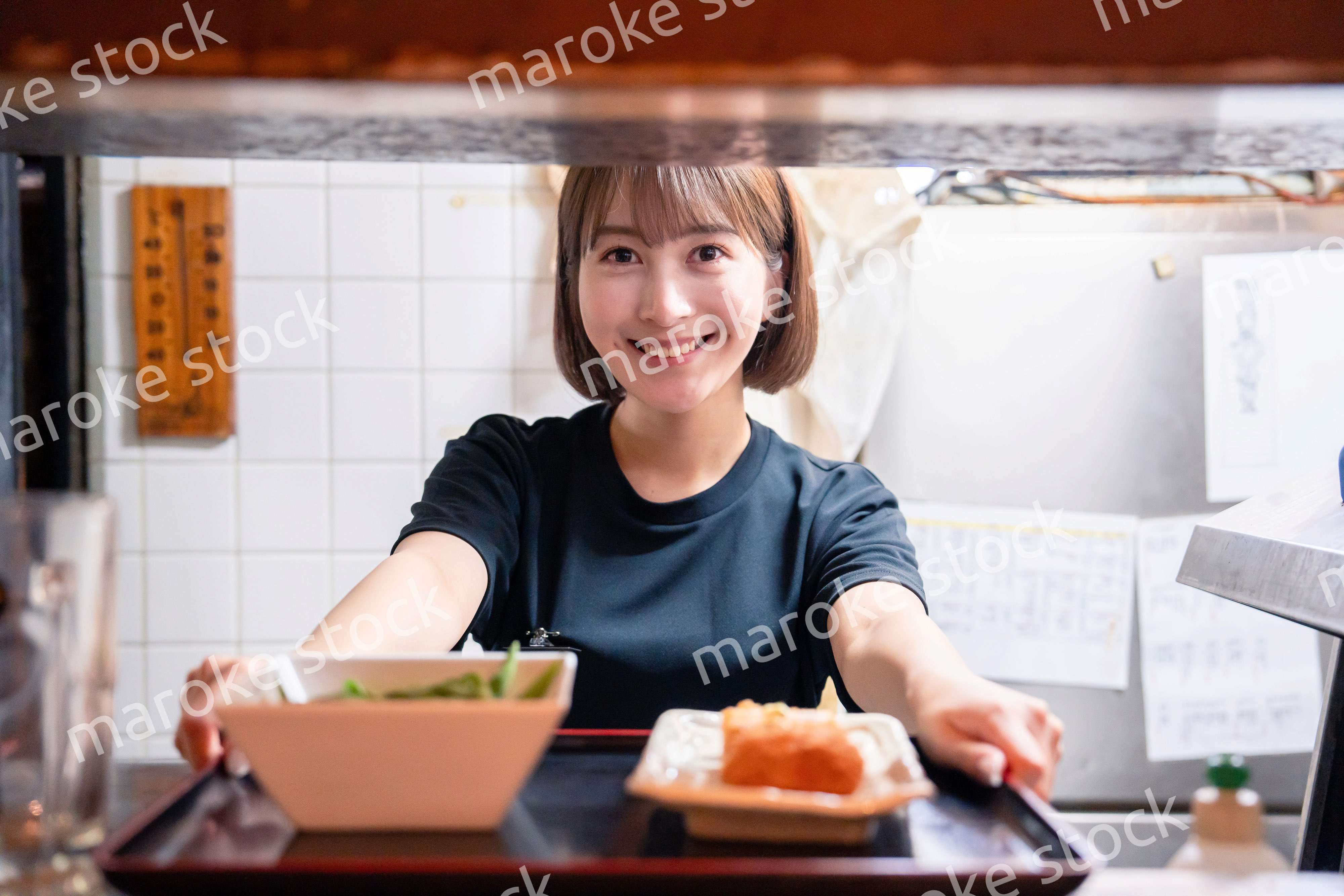 レストランでご飯を提供する若い女性のキッチンスタッフ