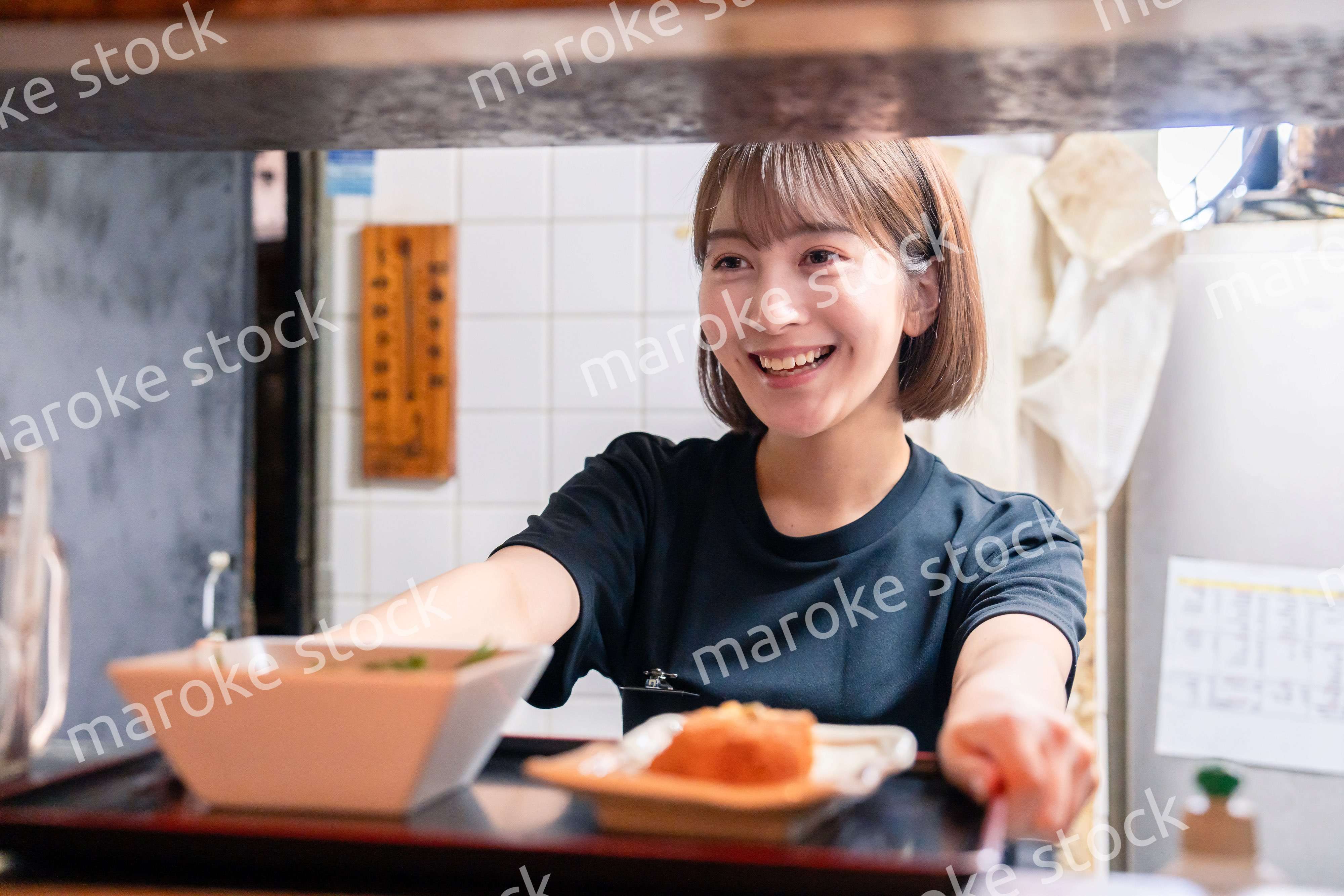 レストランでご飯を提供する若い女性のキッチンスタッフ