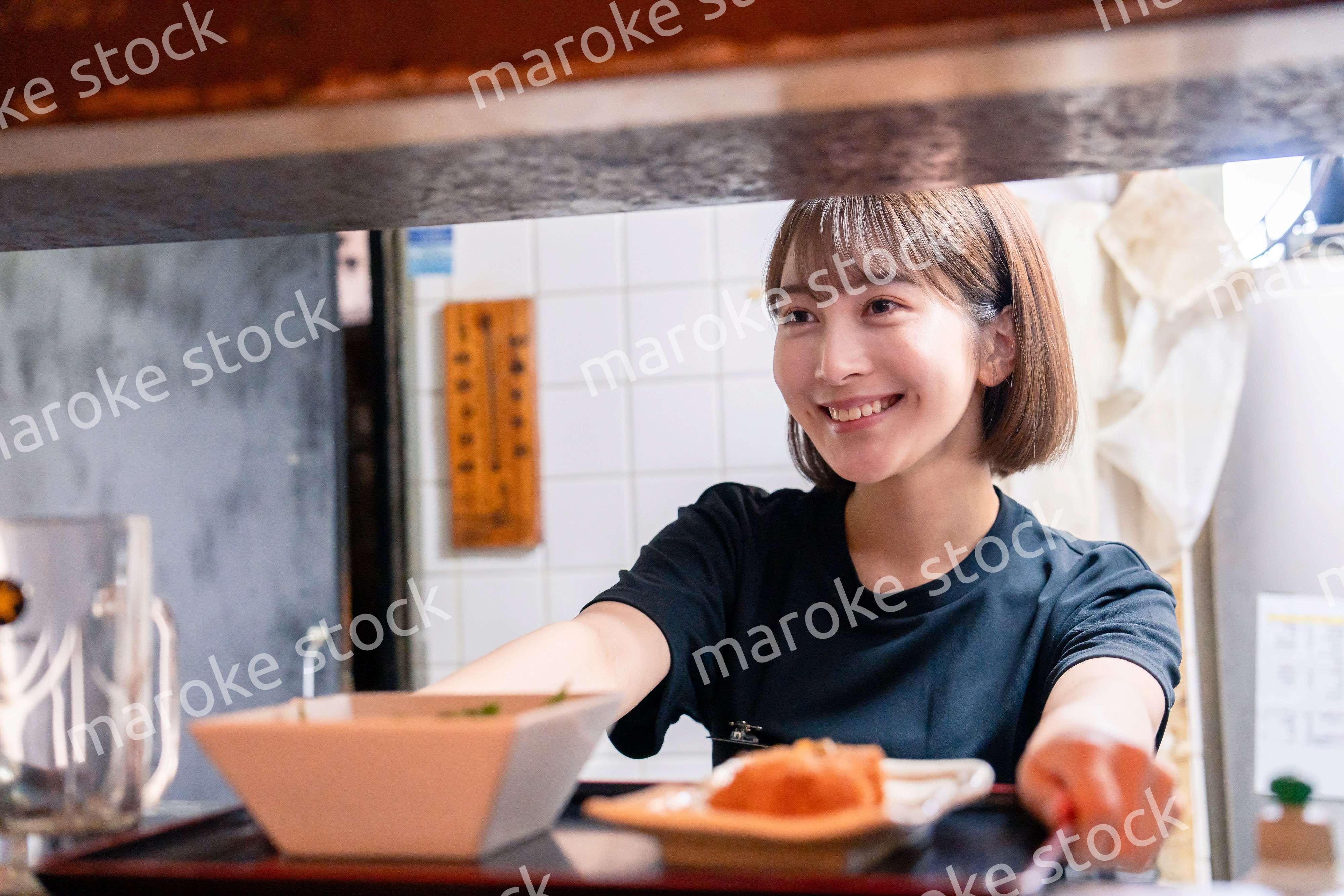 レストランでご飯を提供する若い女性のキッチンスタッフ