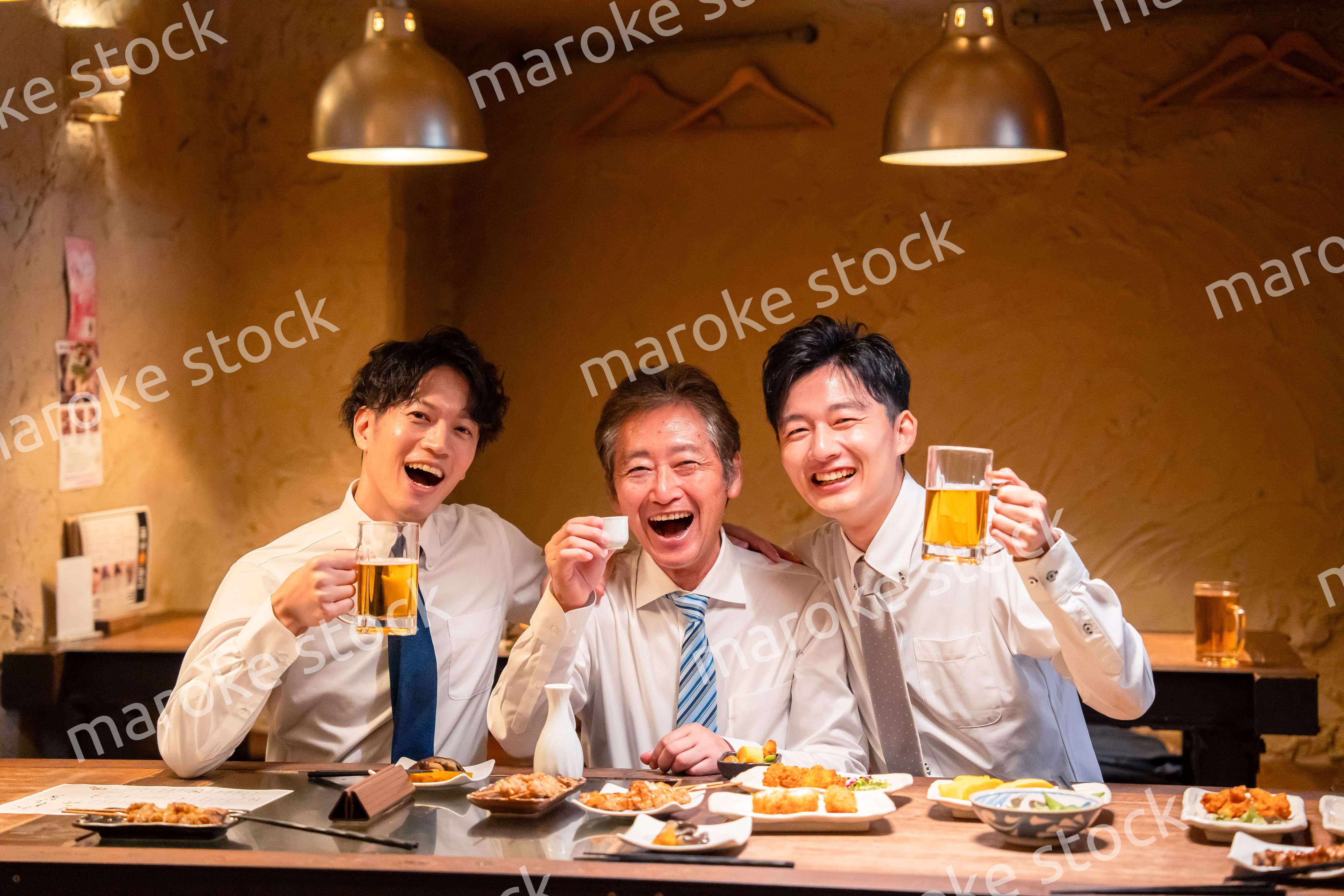 上司と肩を組みながら居酒屋で飲むサラリーマン
