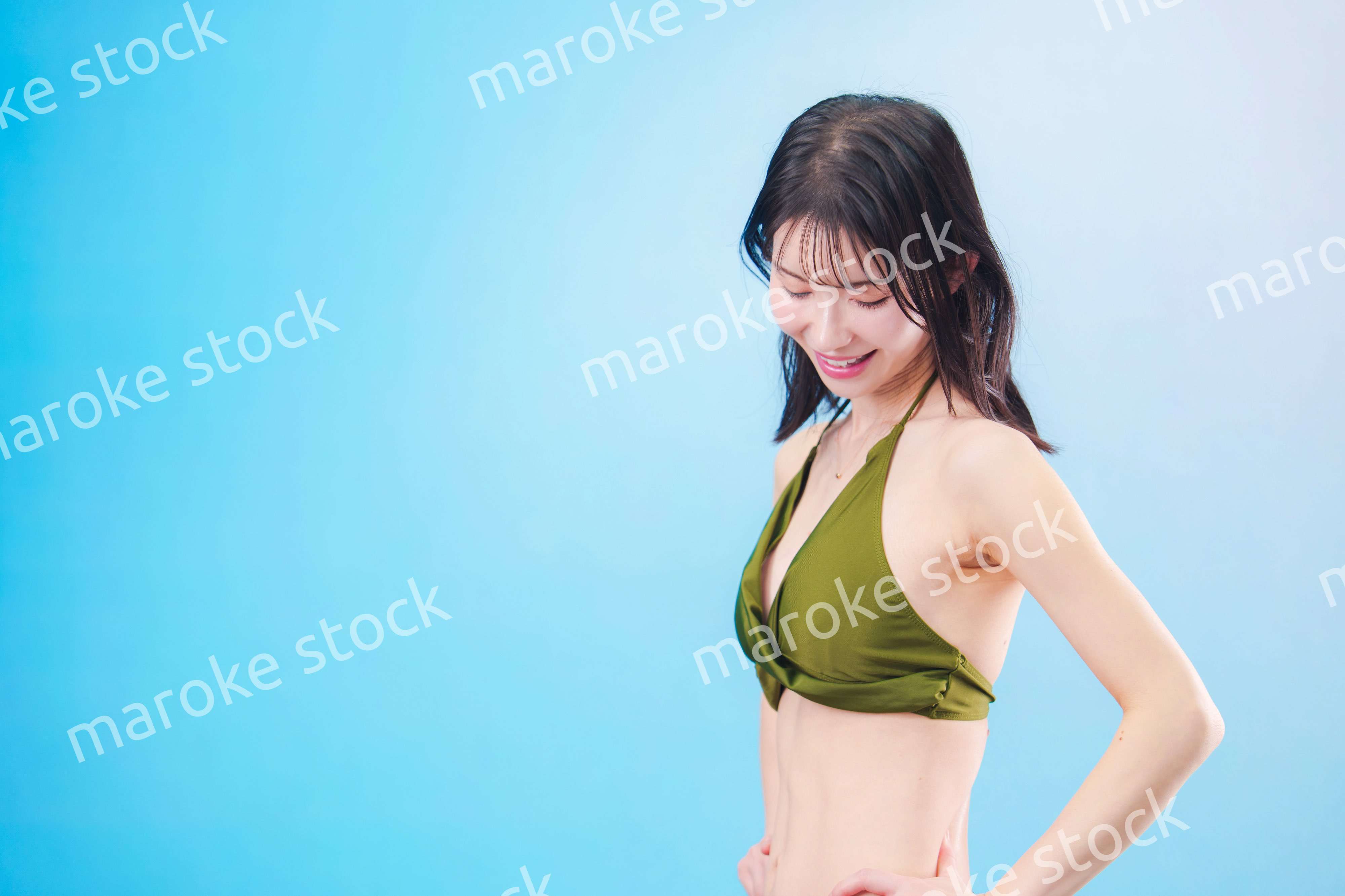 水着を着て夏を満喫する女性（水色背景）