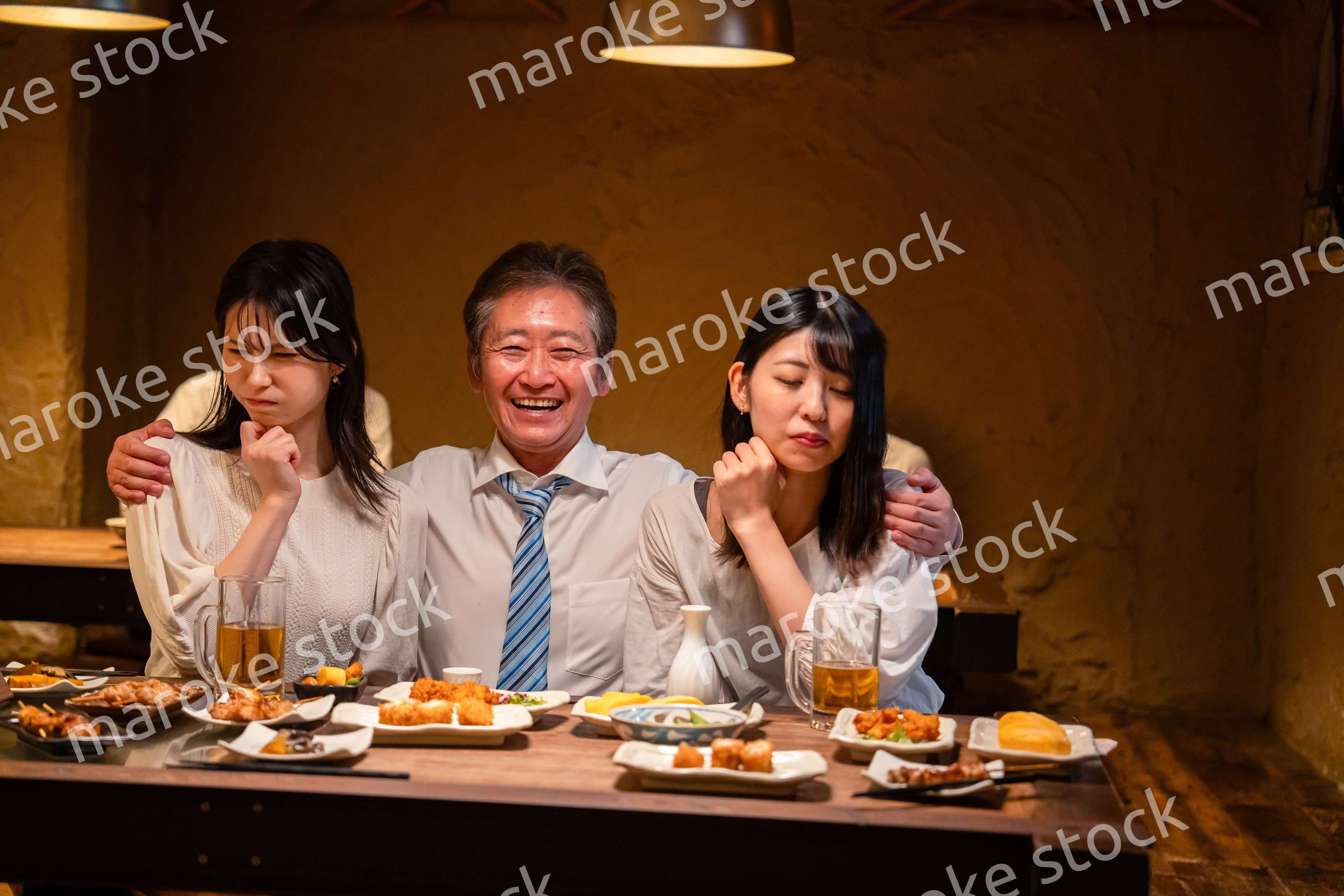 宴会の席で女性と肩を組むビジネスマン