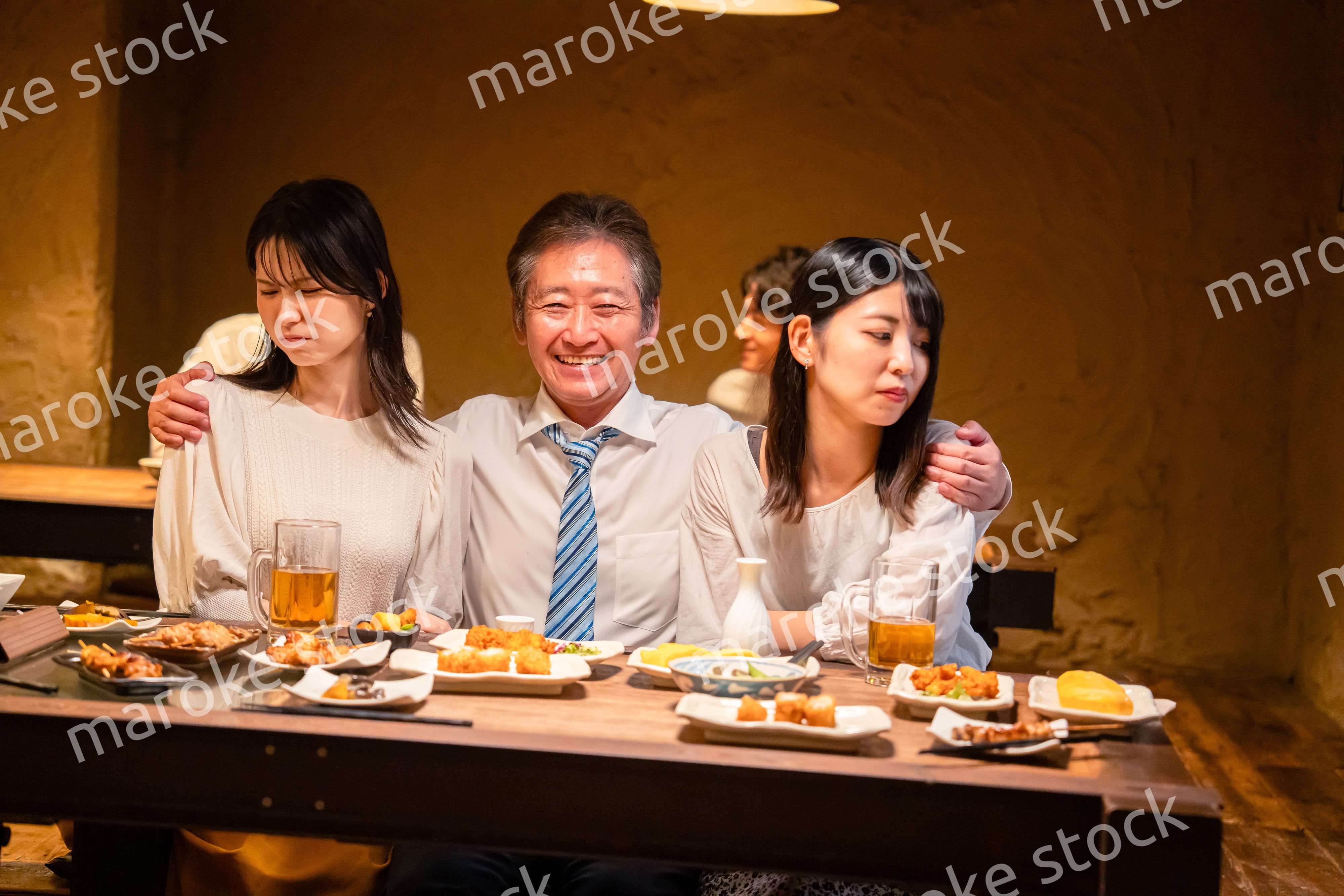 宴会の席で女性と肩を組むビジネスマン