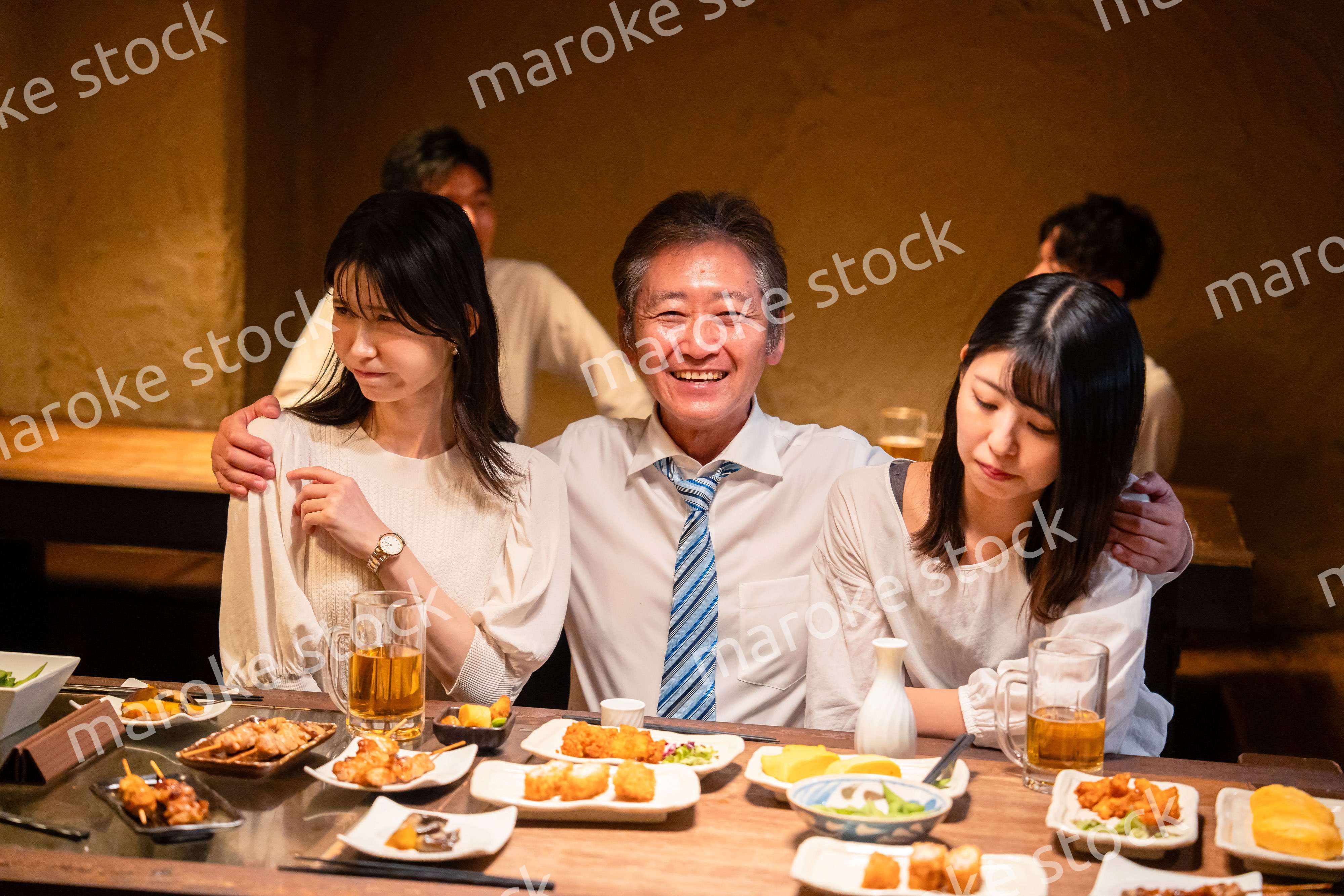 宴会の席で女性と肩を組むビジネスマン