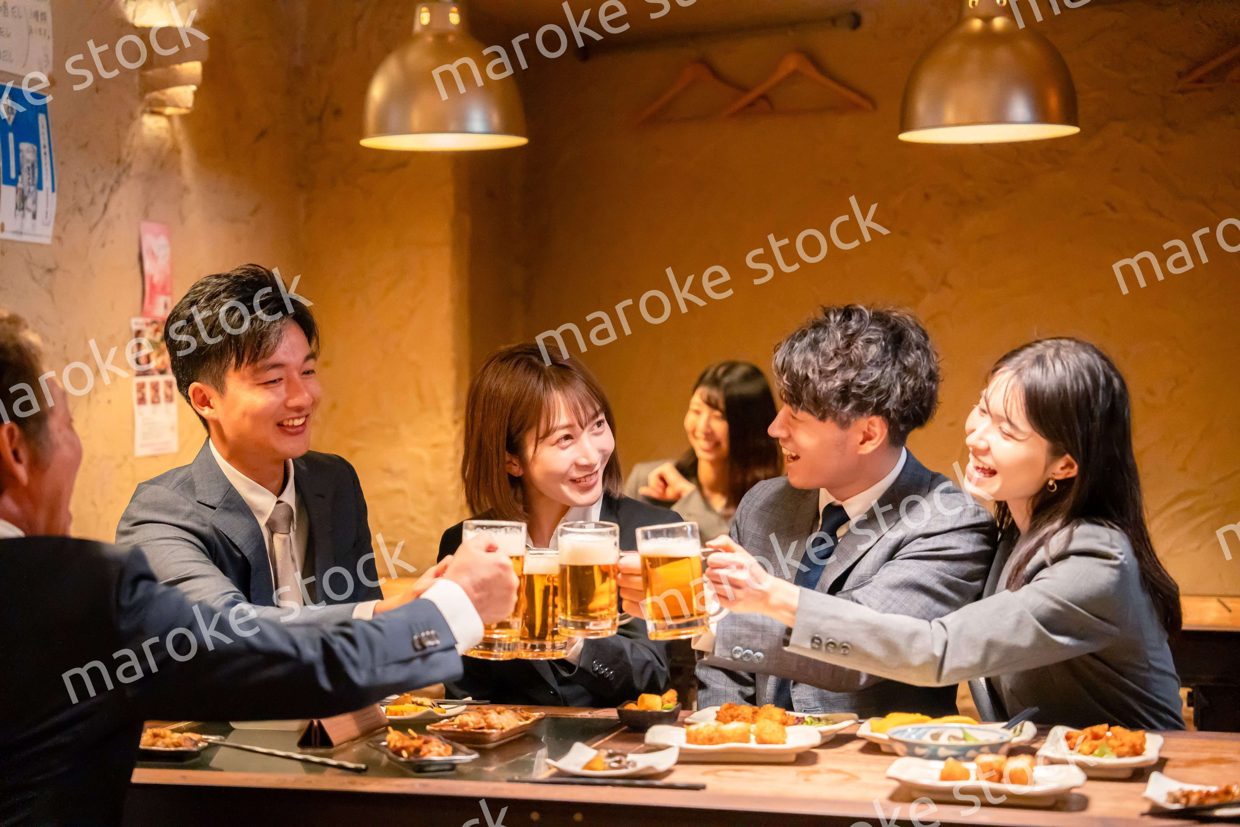 居酒屋で盛大に乾杯をするビジネスパーソン