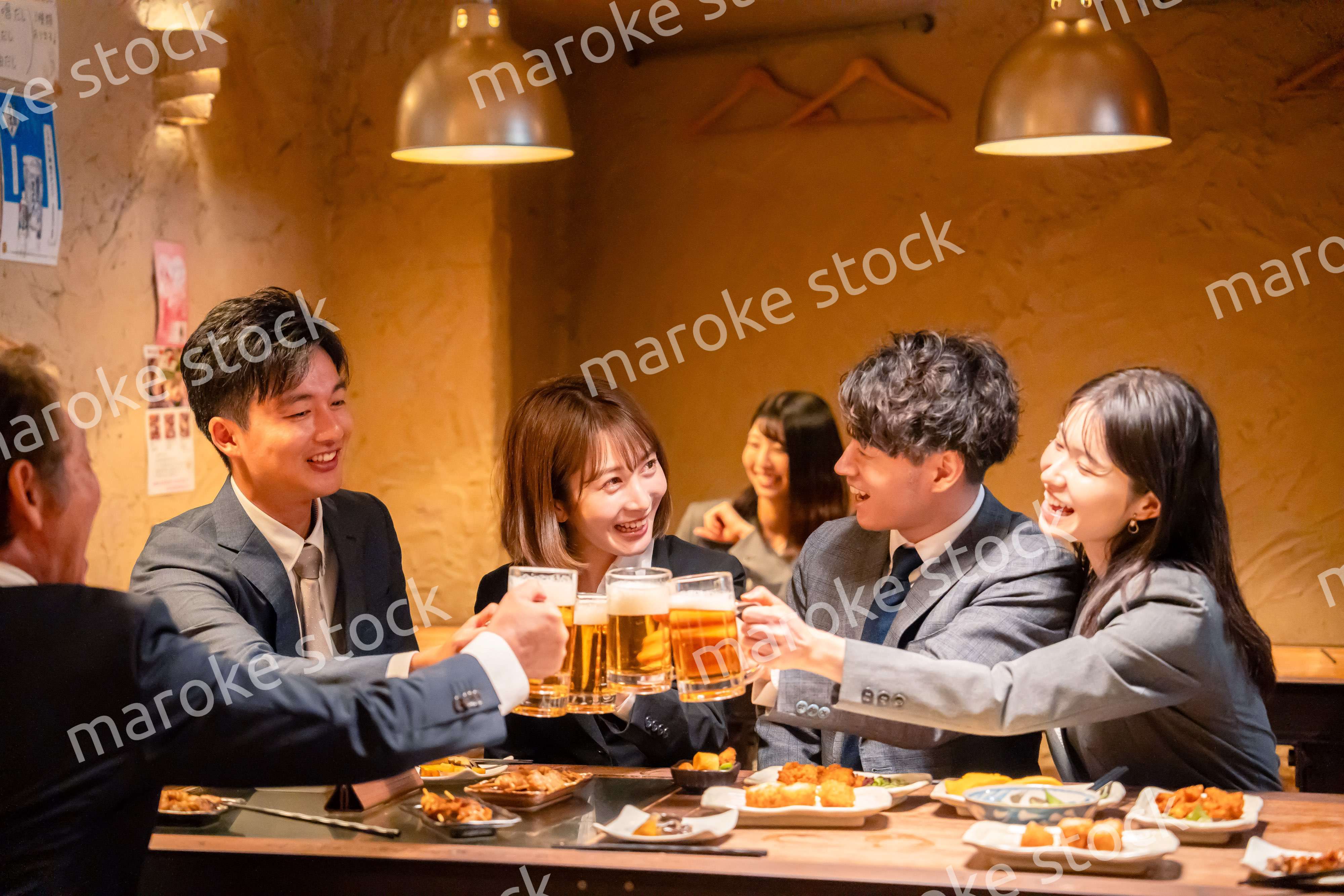 居酒屋で盛大に乾杯をするビジネスパーソン