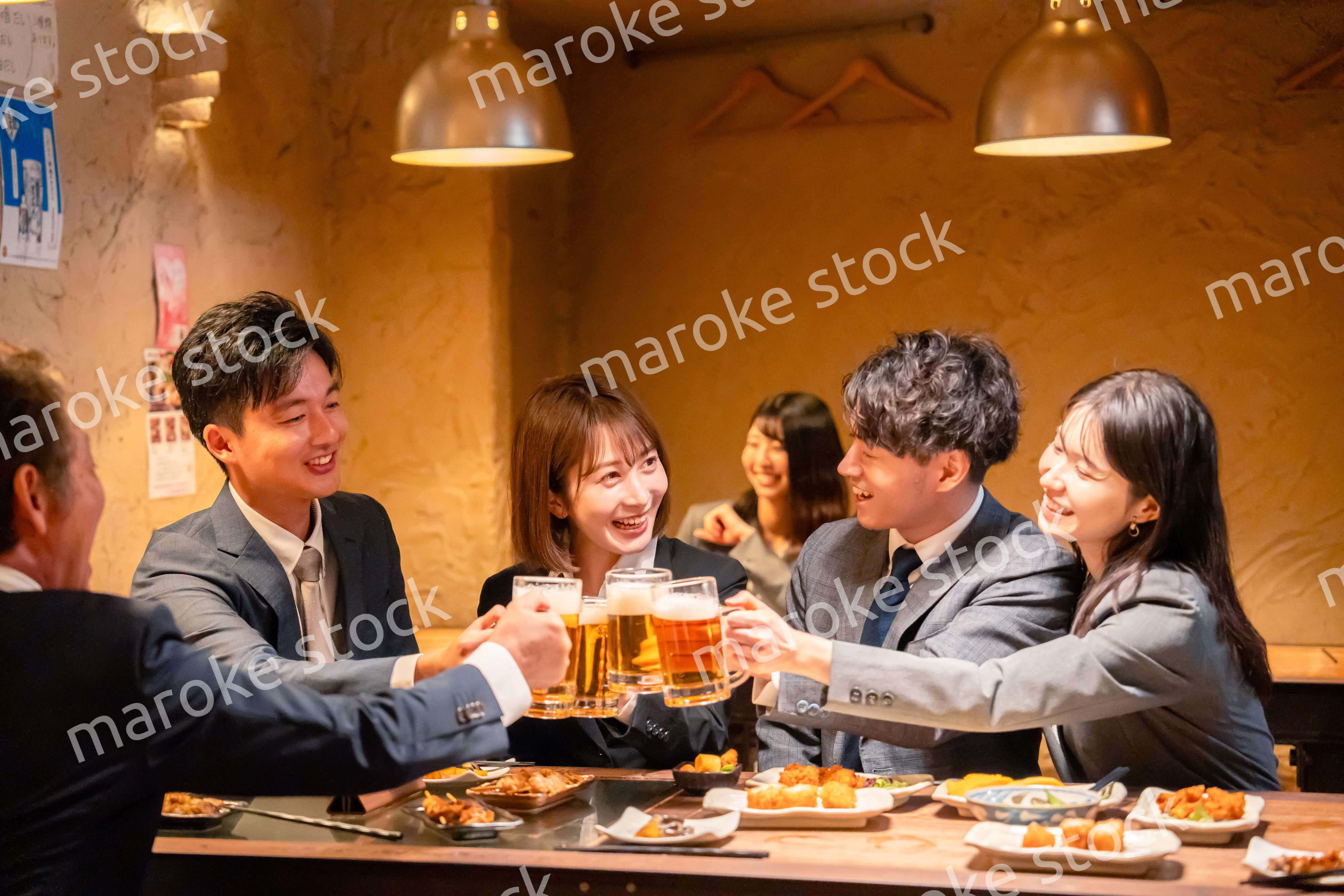 居酒屋で盛大に乾杯をするビジネスパーソン