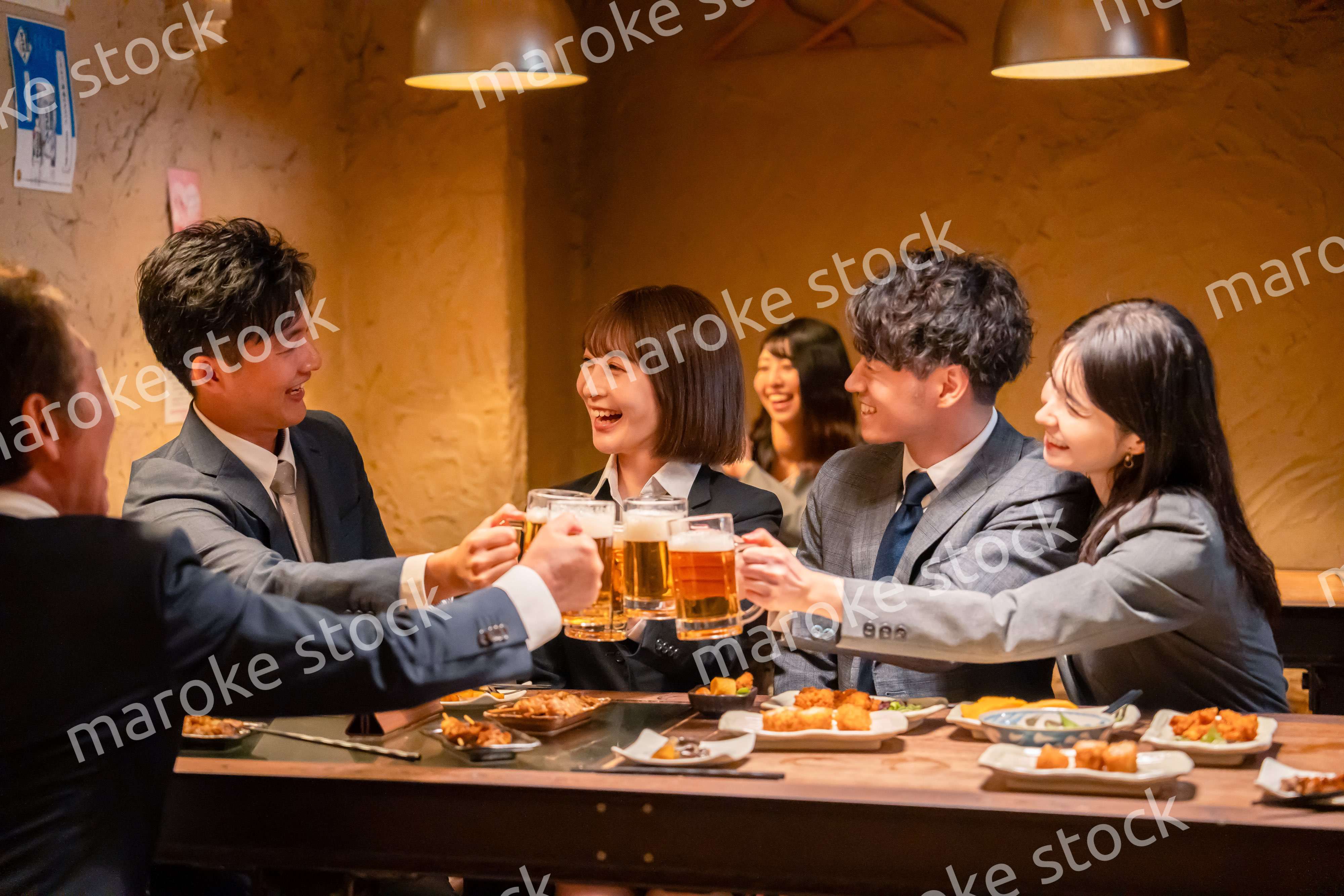 居酒屋で盛大に乾杯をするビジネスパーソン