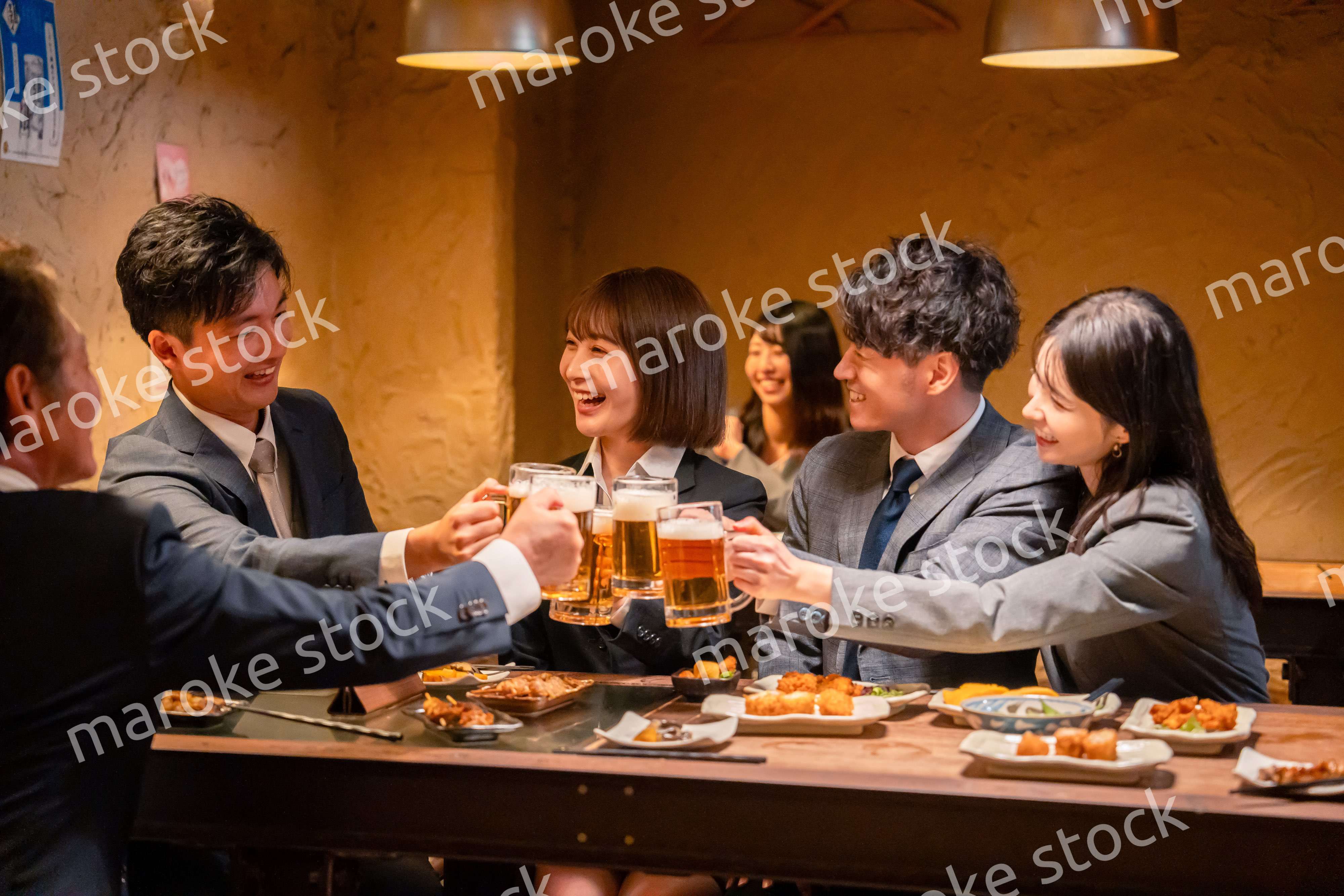 居酒屋で盛大に乾杯をするビジネスパーソン