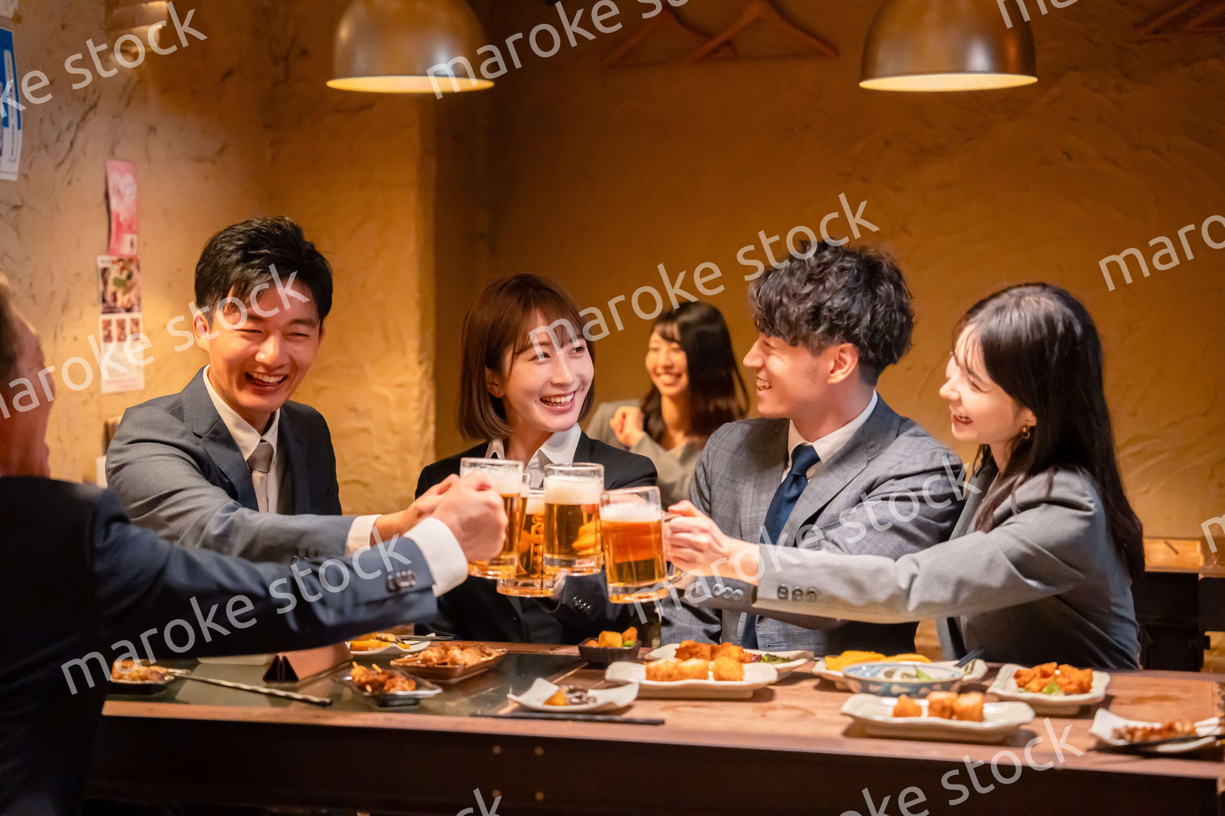 居酒屋で盛大に乾杯をするビジネスパーソン