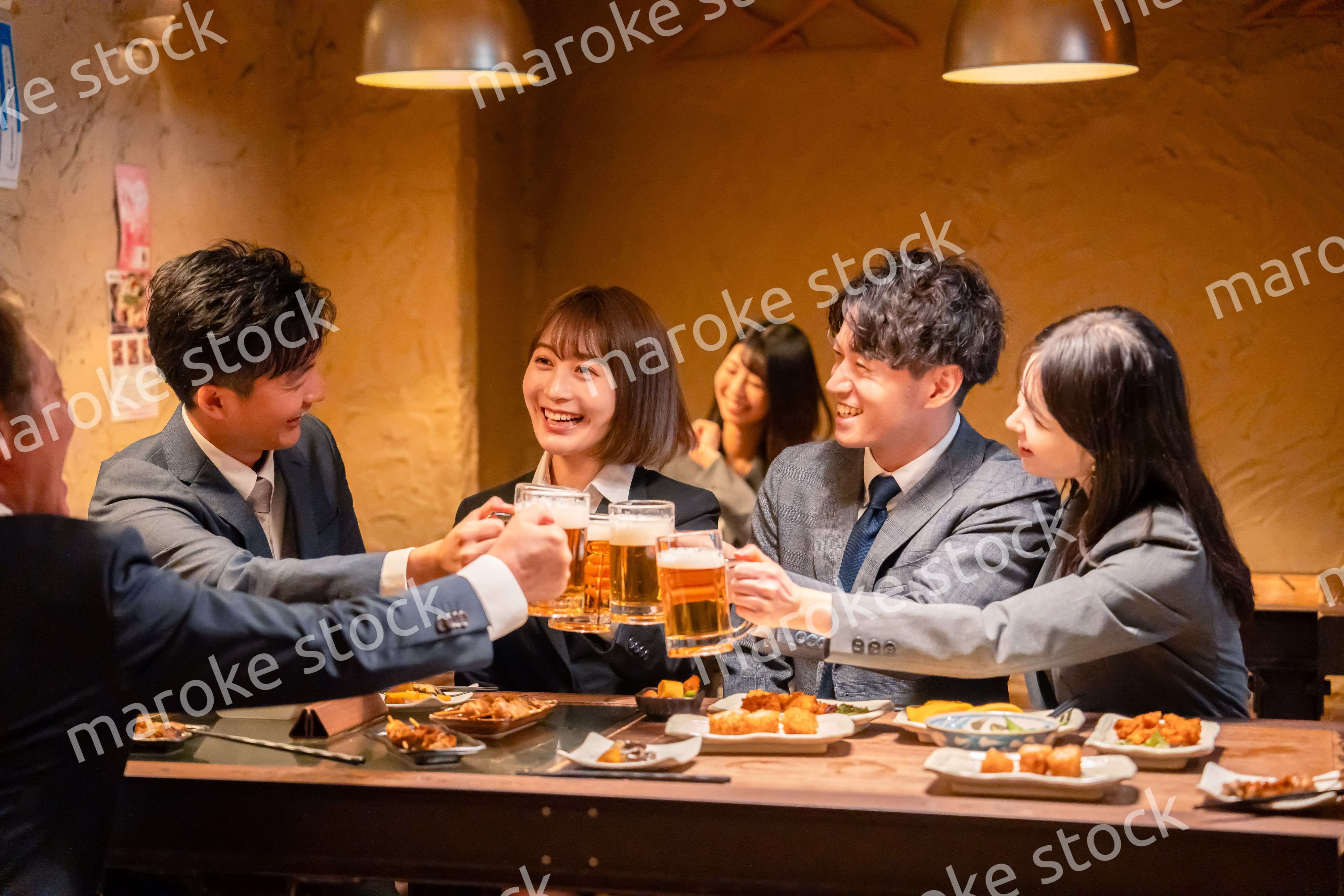 居酒屋で盛大に乾杯をするビジネスパーソン