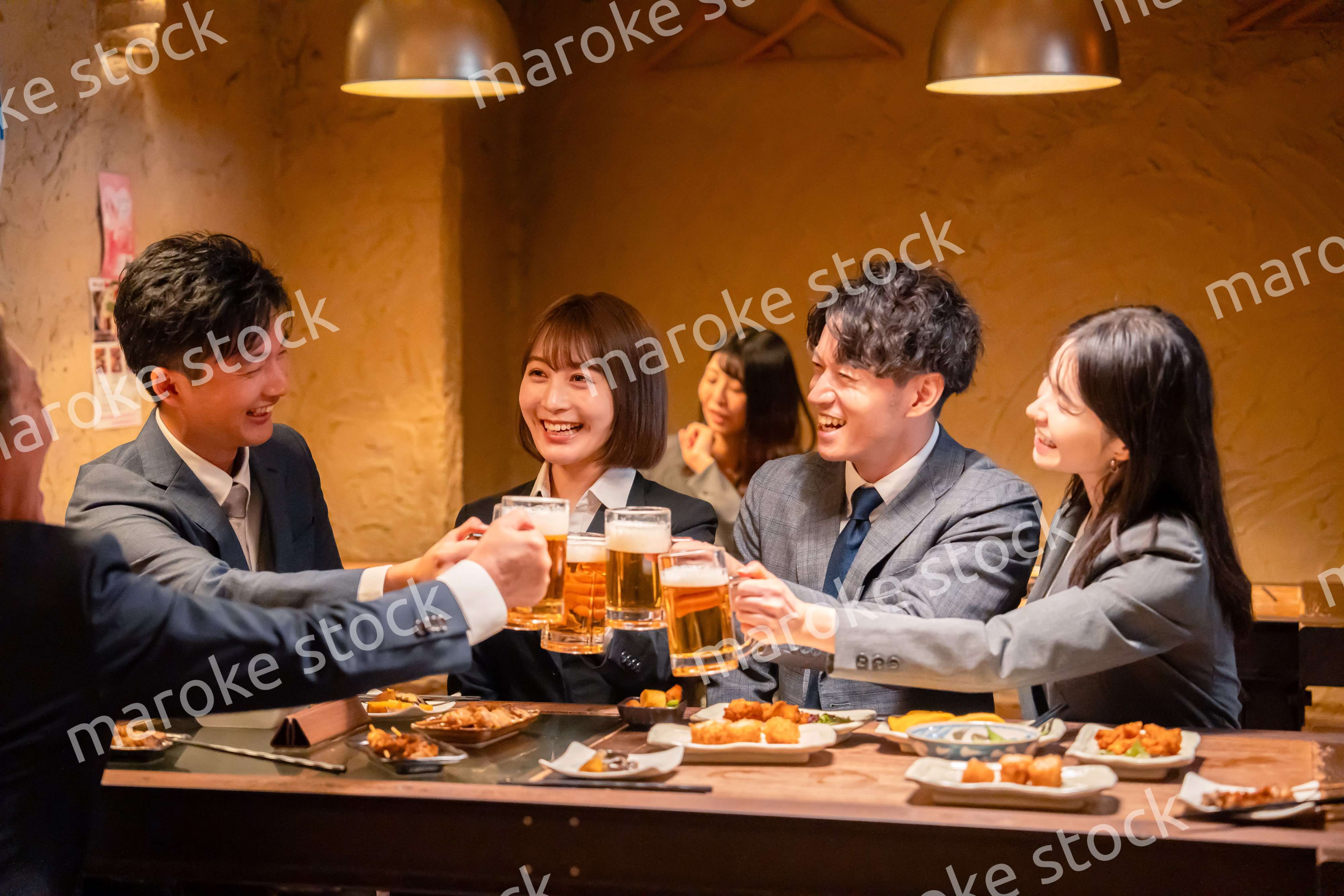 居酒屋で盛大に乾杯をするビジネスパーソン