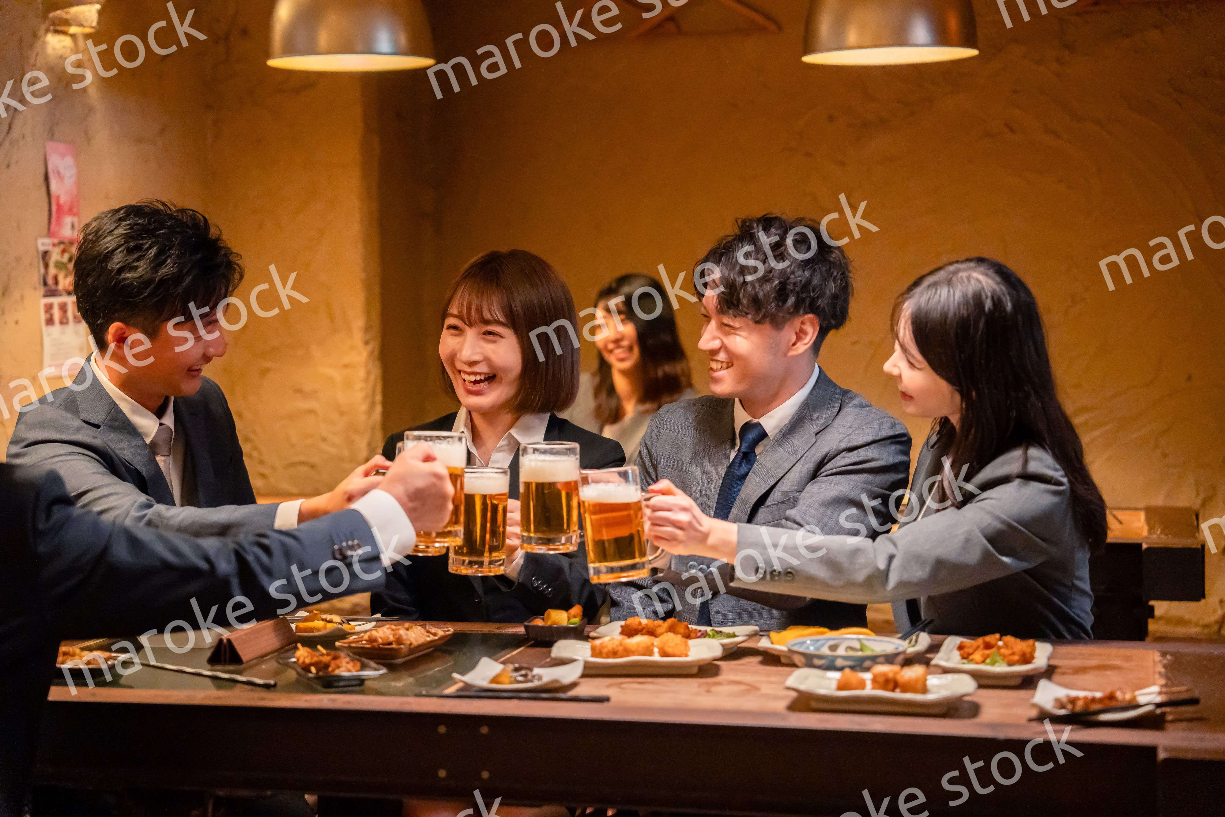 居酒屋で盛大に乾杯をするビジネスパーソン