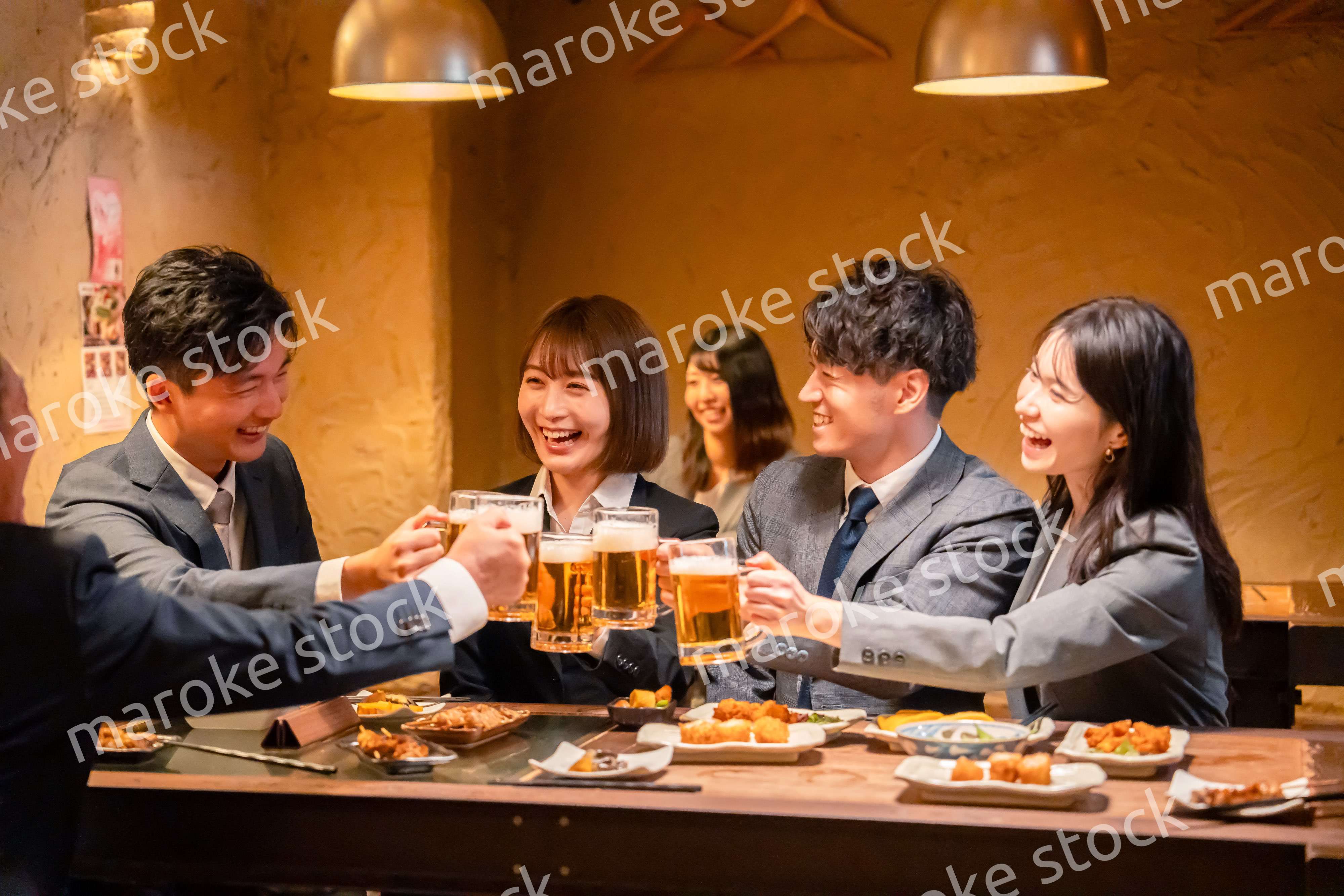 居酒屋で盛大に乾杯をするビジネスパーソン