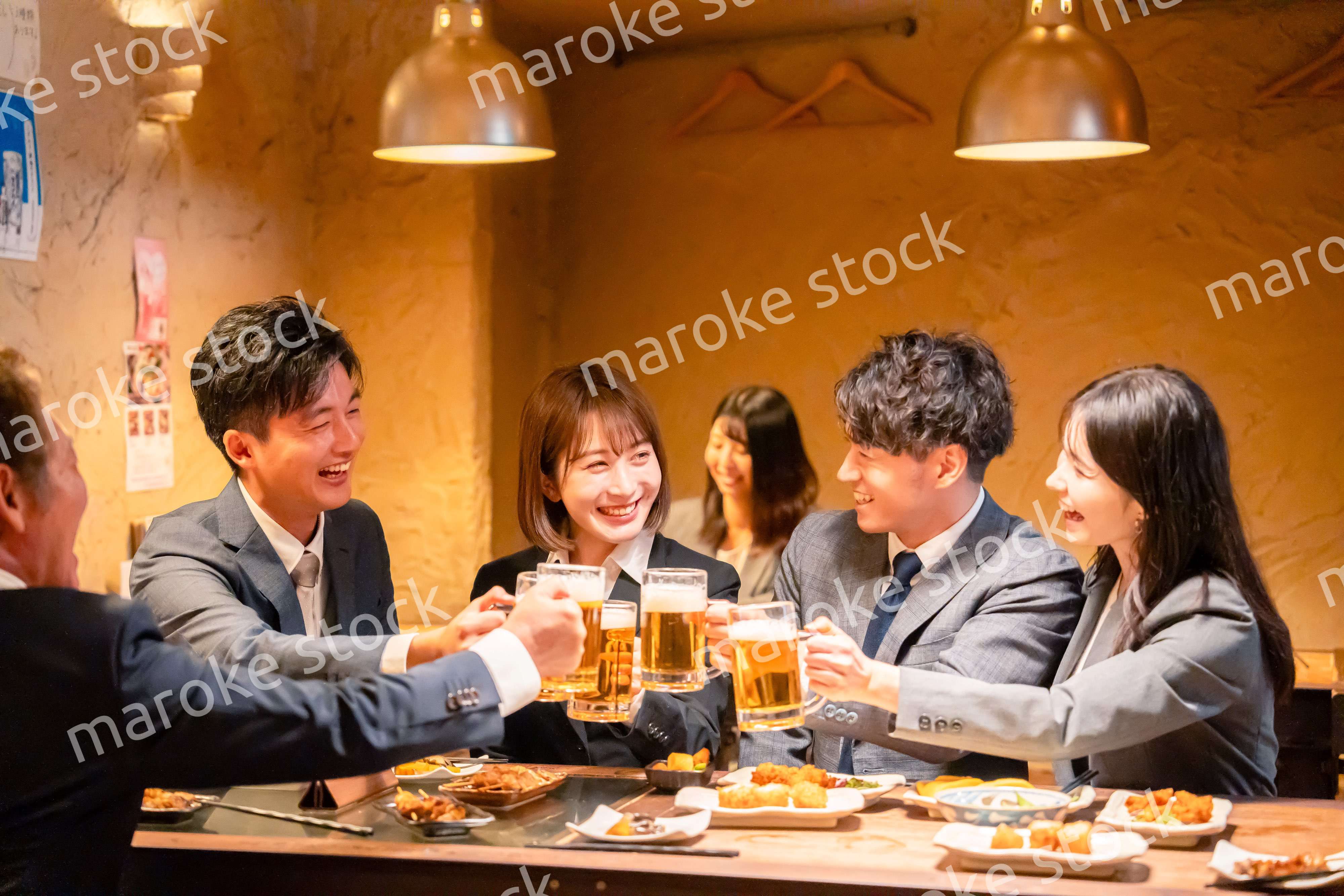 居酒屋で盛大に乾杯をするビジネスパーソン