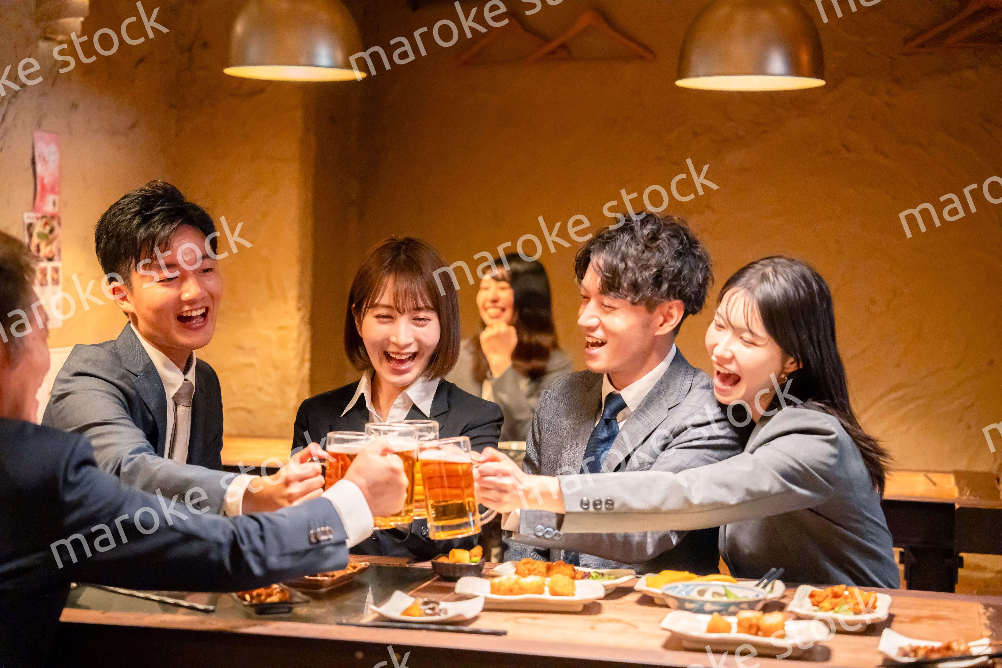 居酒屋で盛大に乾杯をするビジネスパーソン