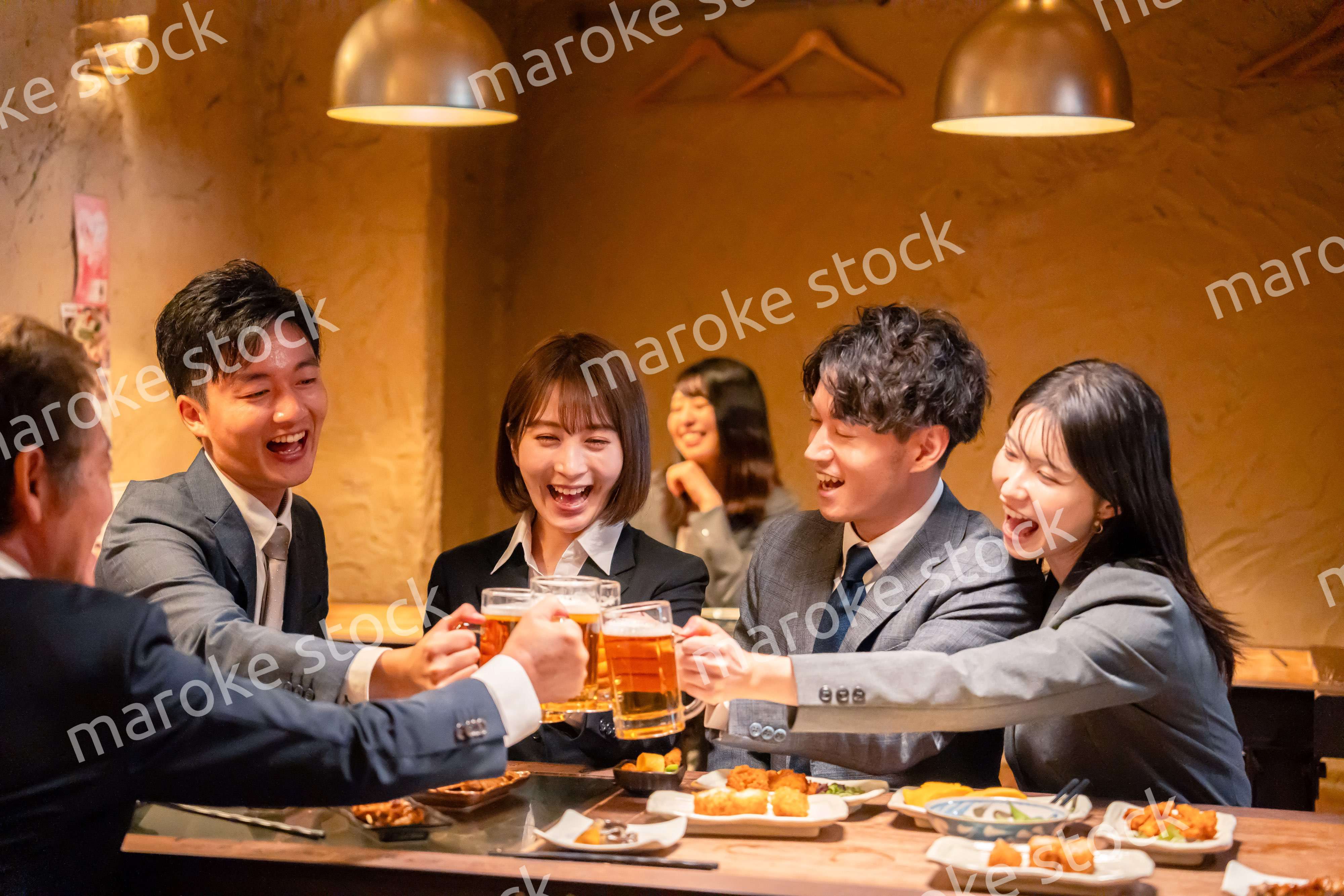 居酒屋で盛大に乾杯をするビジネスパーソン