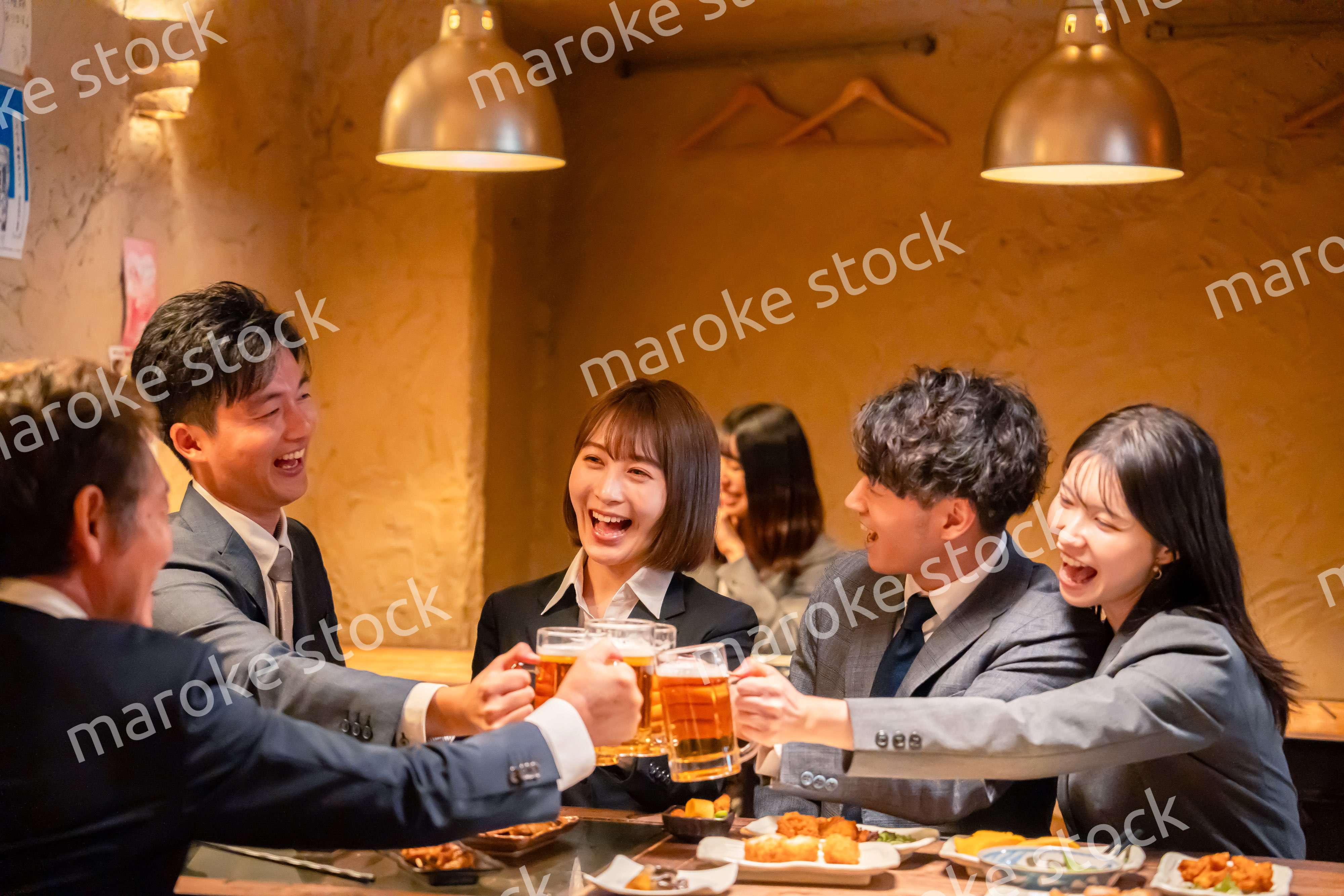 居酒屋で盛大に乾杯をするビジネスパーソン