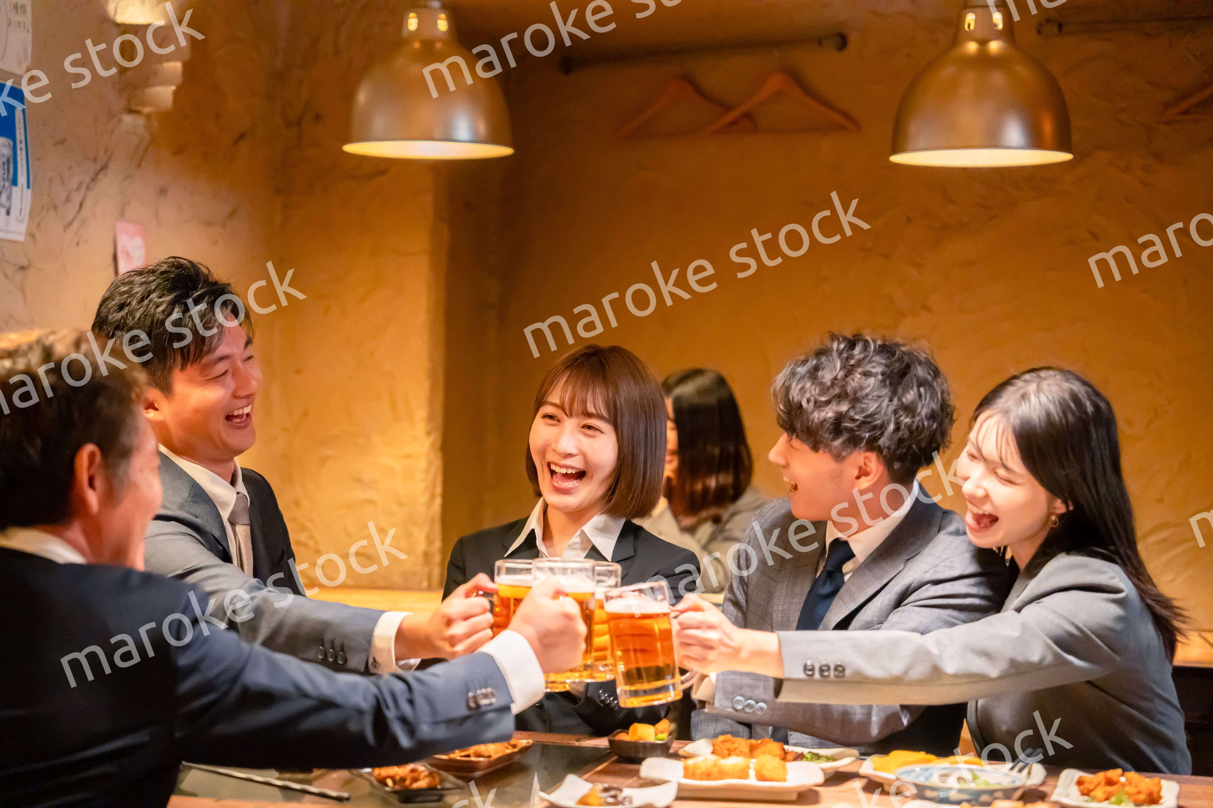 居酒屋で盛大に乾杯をするビジネスパーソン