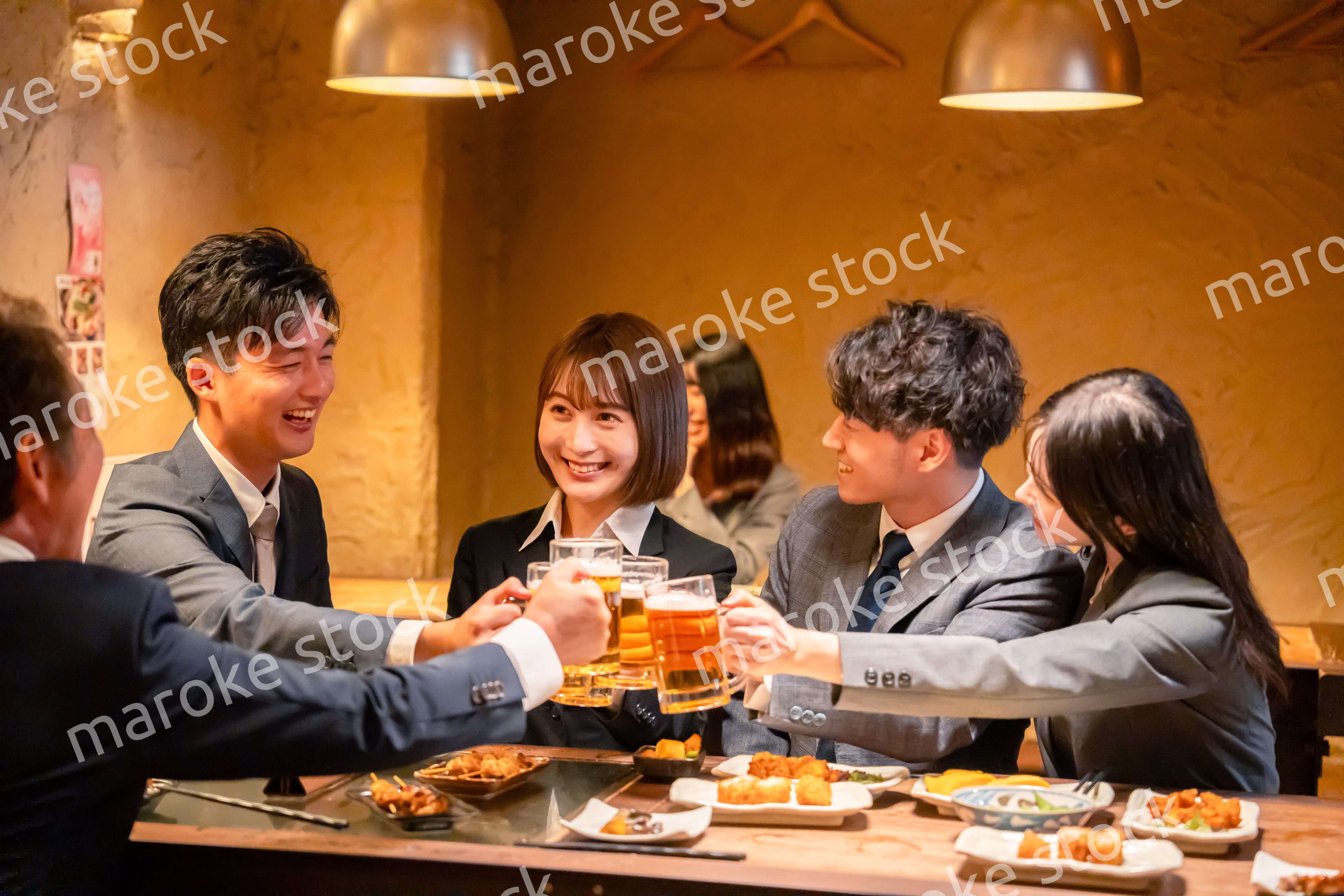 居酒屋で盛大に乾杯をするビジネスパーソン