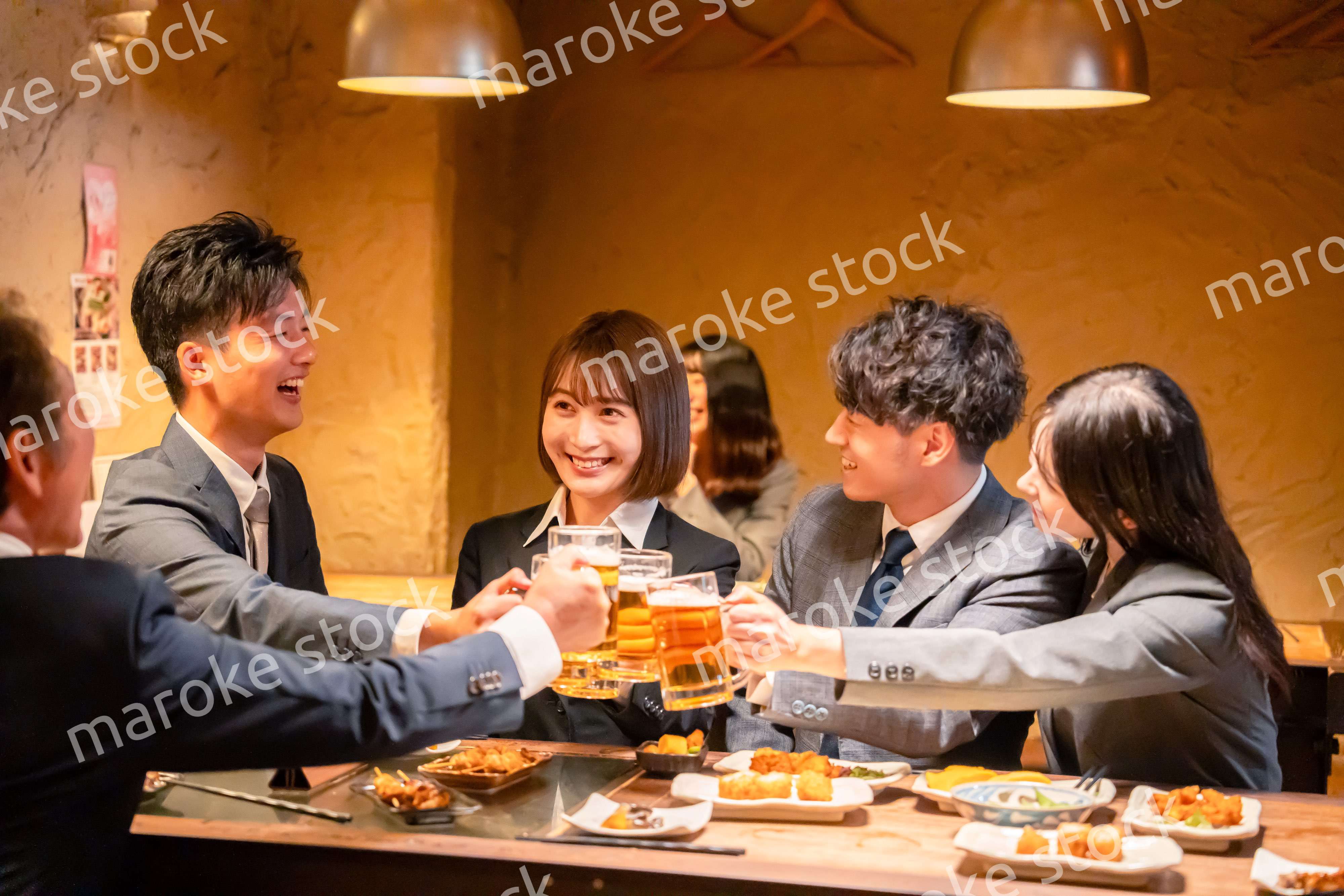 居酒屋で盛大に乾杯をするビジネスパーソン