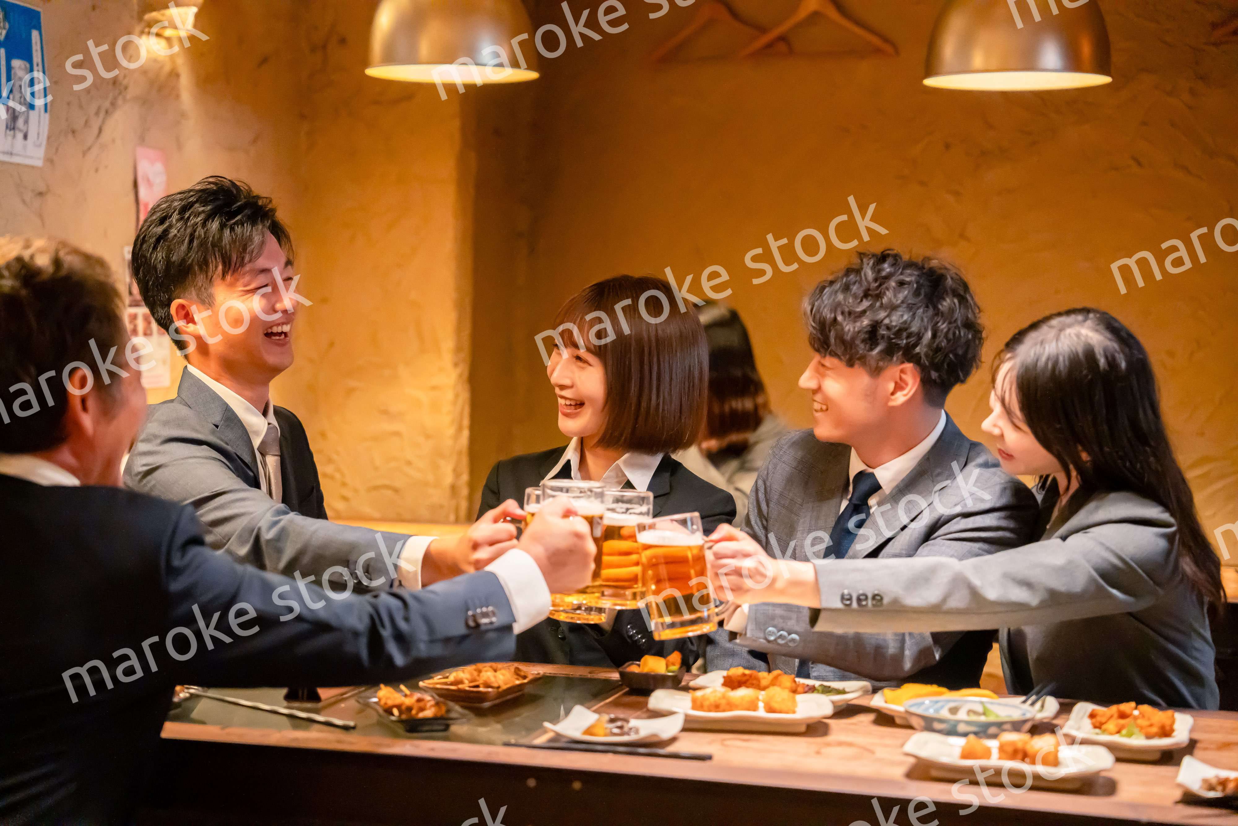 居酒屋で盛大に乾杯をするビジネスパーソン