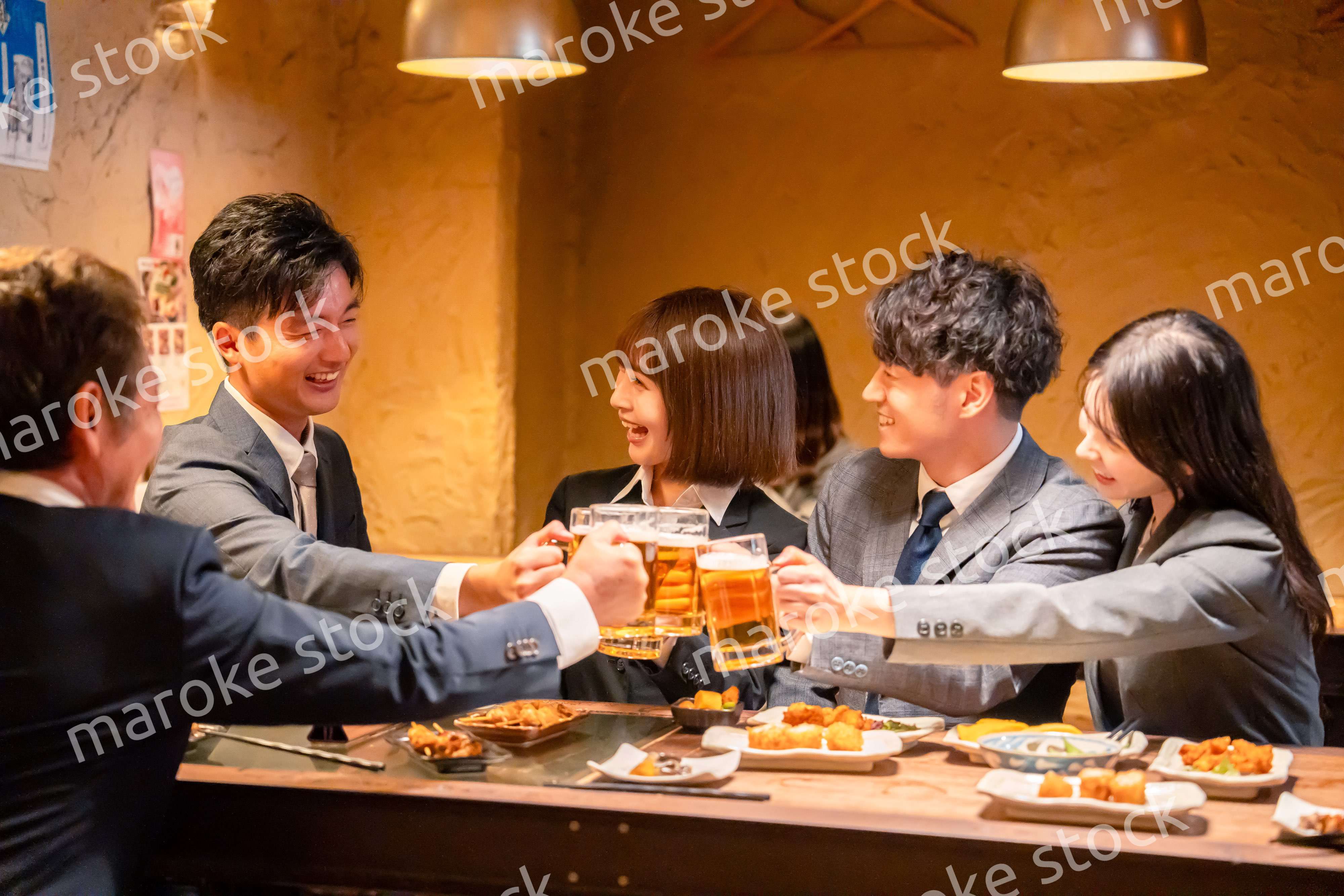 居酒屋で盛大に乾杯をするビジネスパーソン