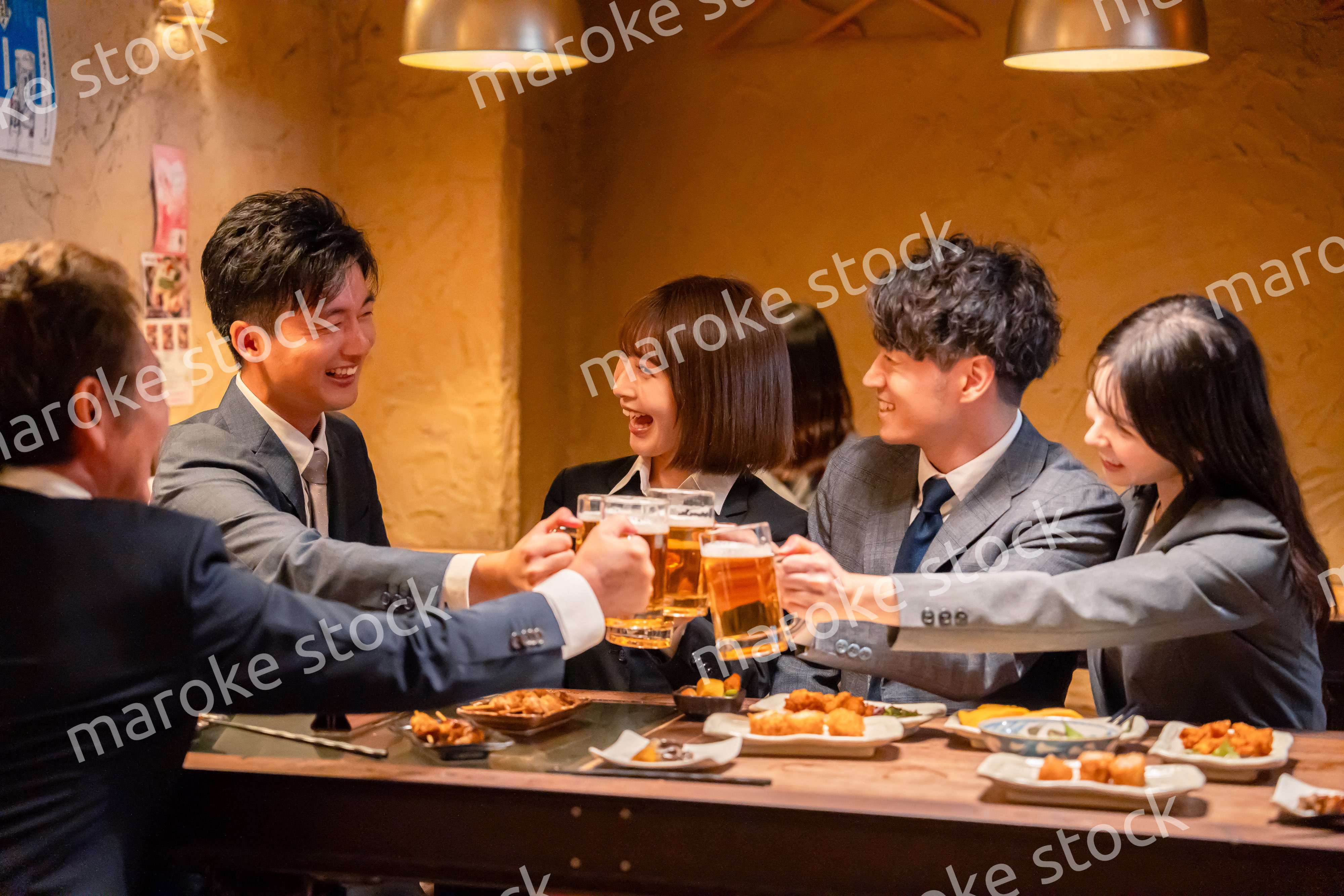居酒屋で盛大に乾杯をするビジネスパーソン