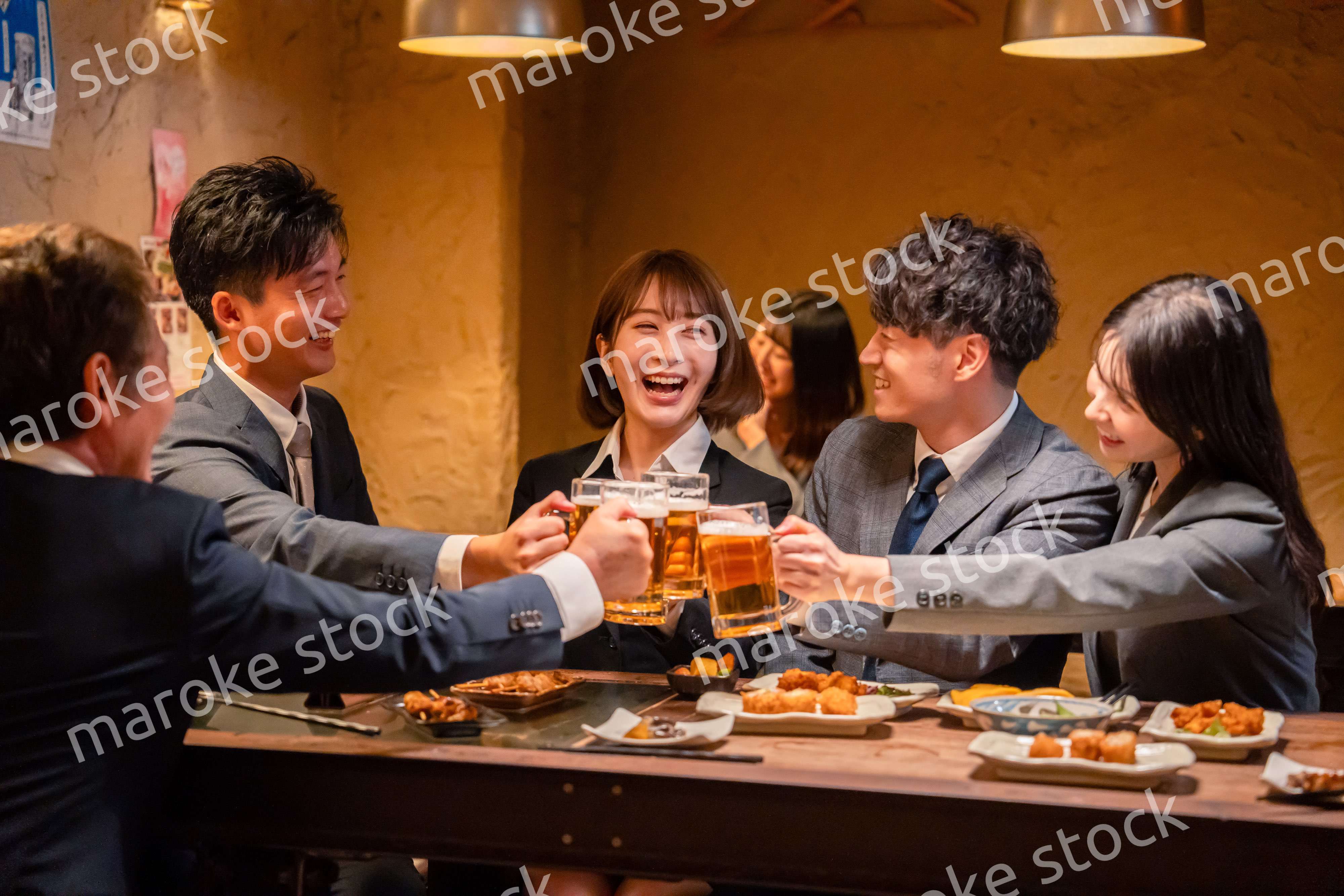 居酒屋で盛大に乾杯をするビジネスパーソン