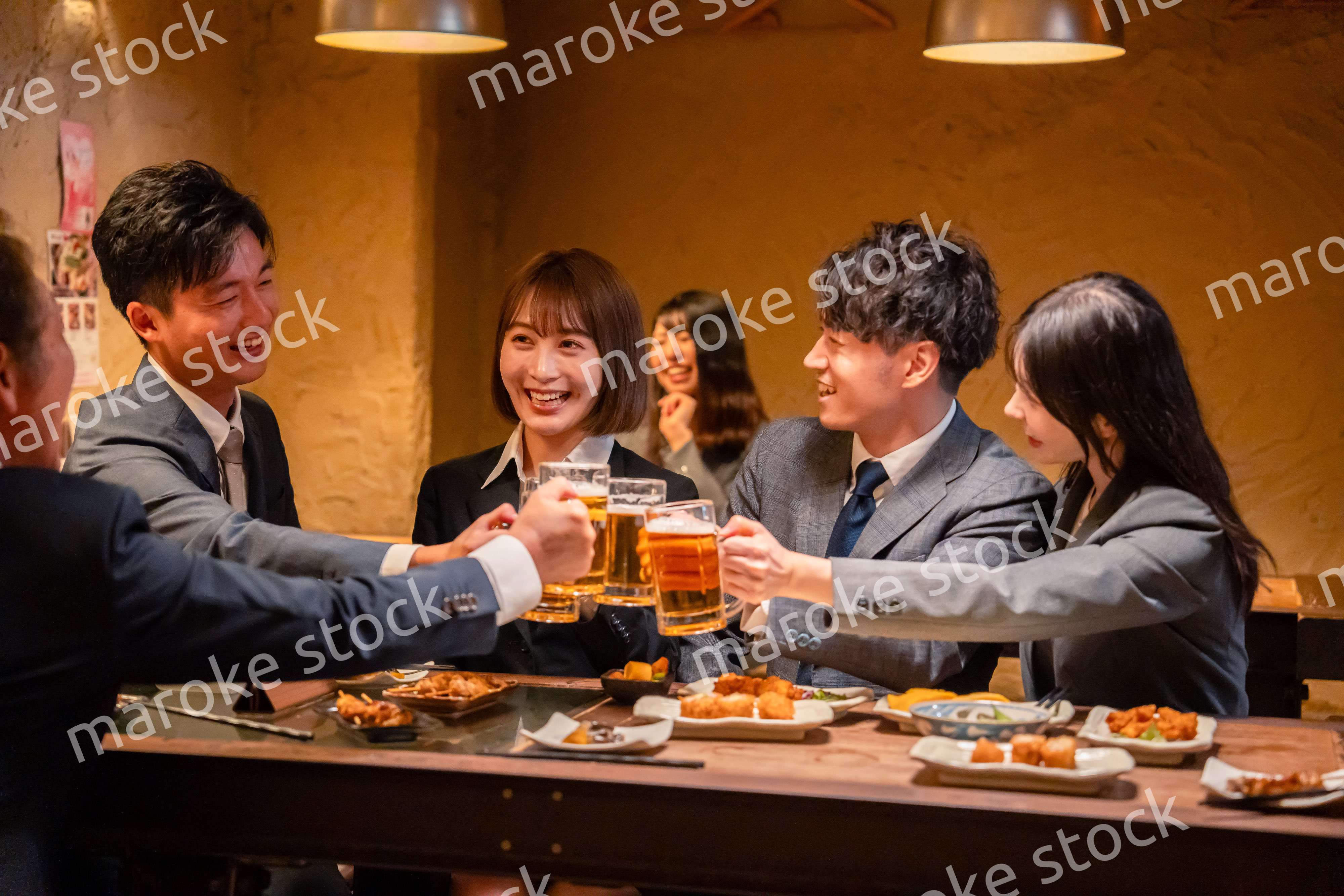 居酒屋で盛大に乾杯をするビジネスパーソン