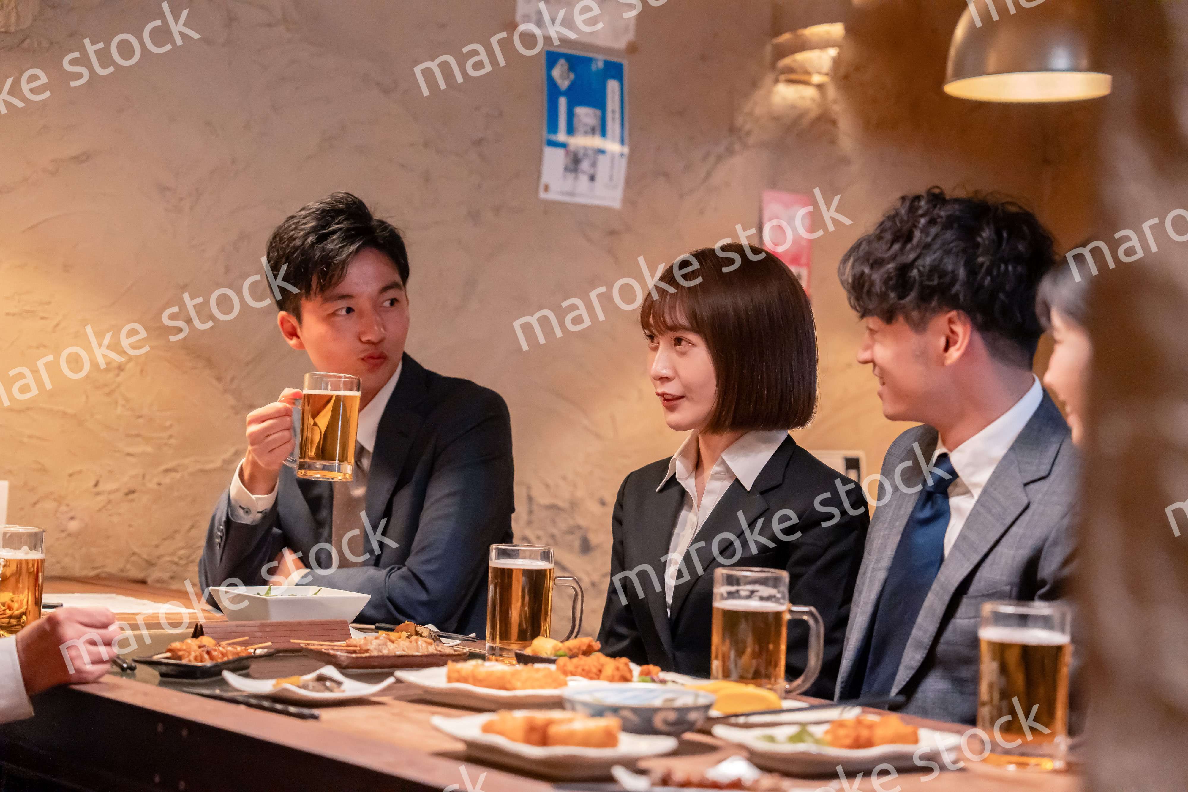 居酒屋で新入社員の歓迎会をするビジネスパーソン