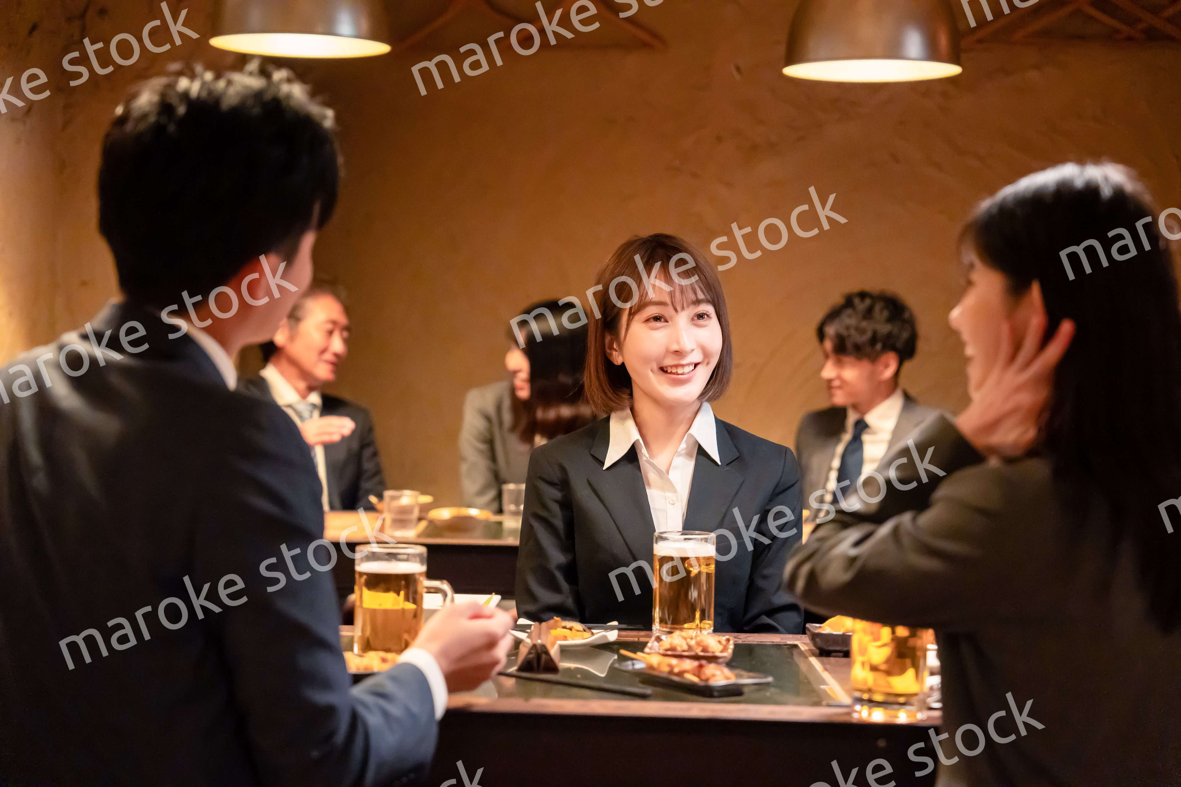 居酒屋で先輩社員とお酒を飲む新入社員