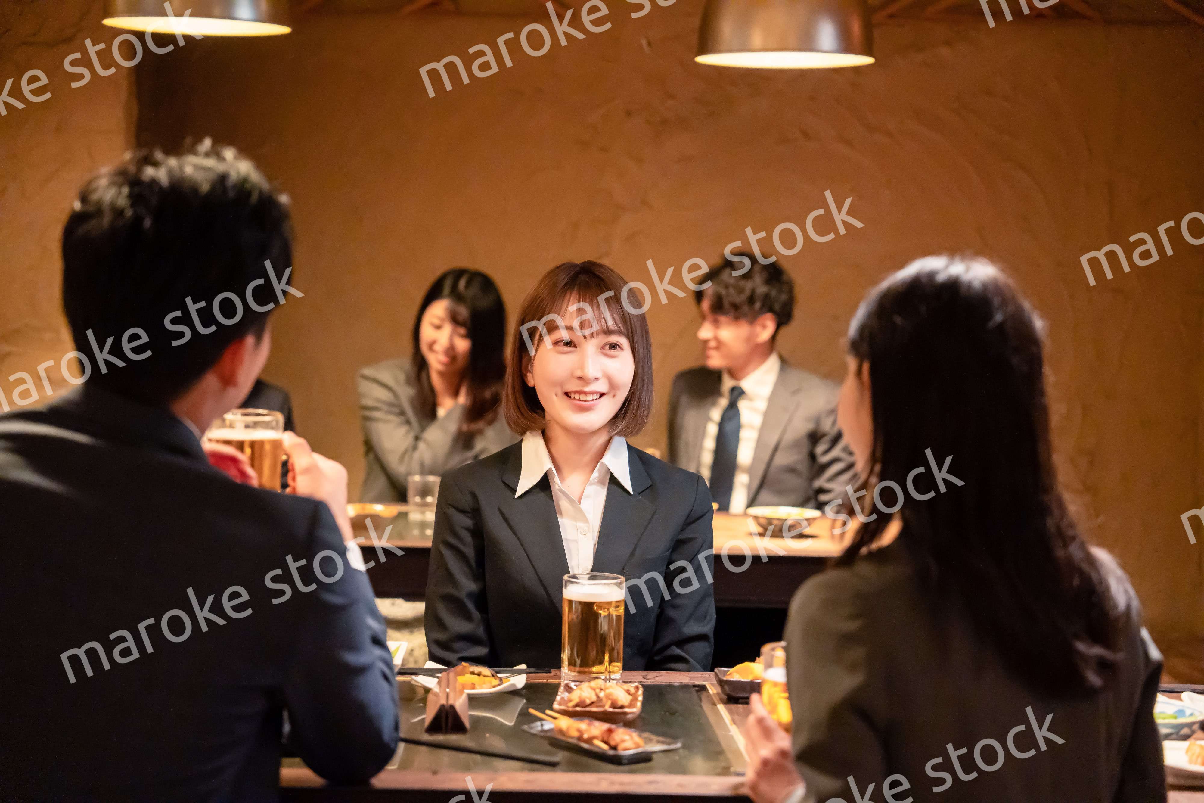 居酒屋で先輩社員とお酒を飲む新入社員