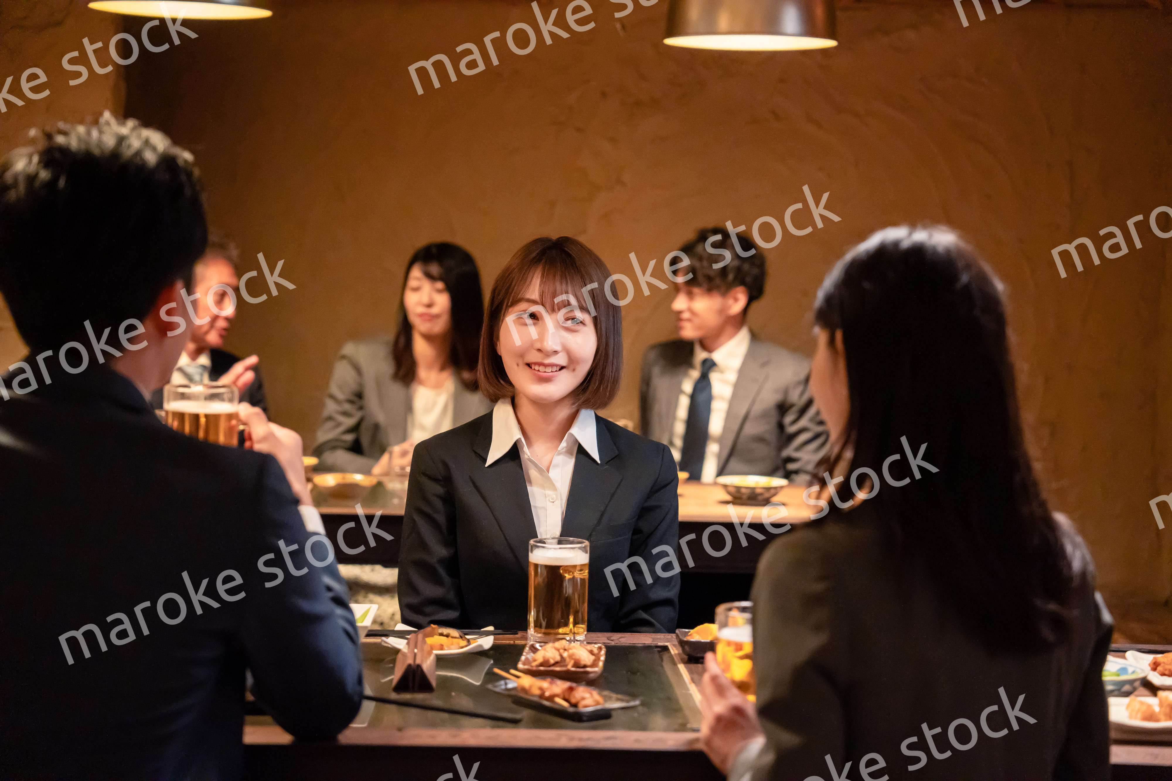 居酒屋で先輩社員とお酒を飲む新入社員