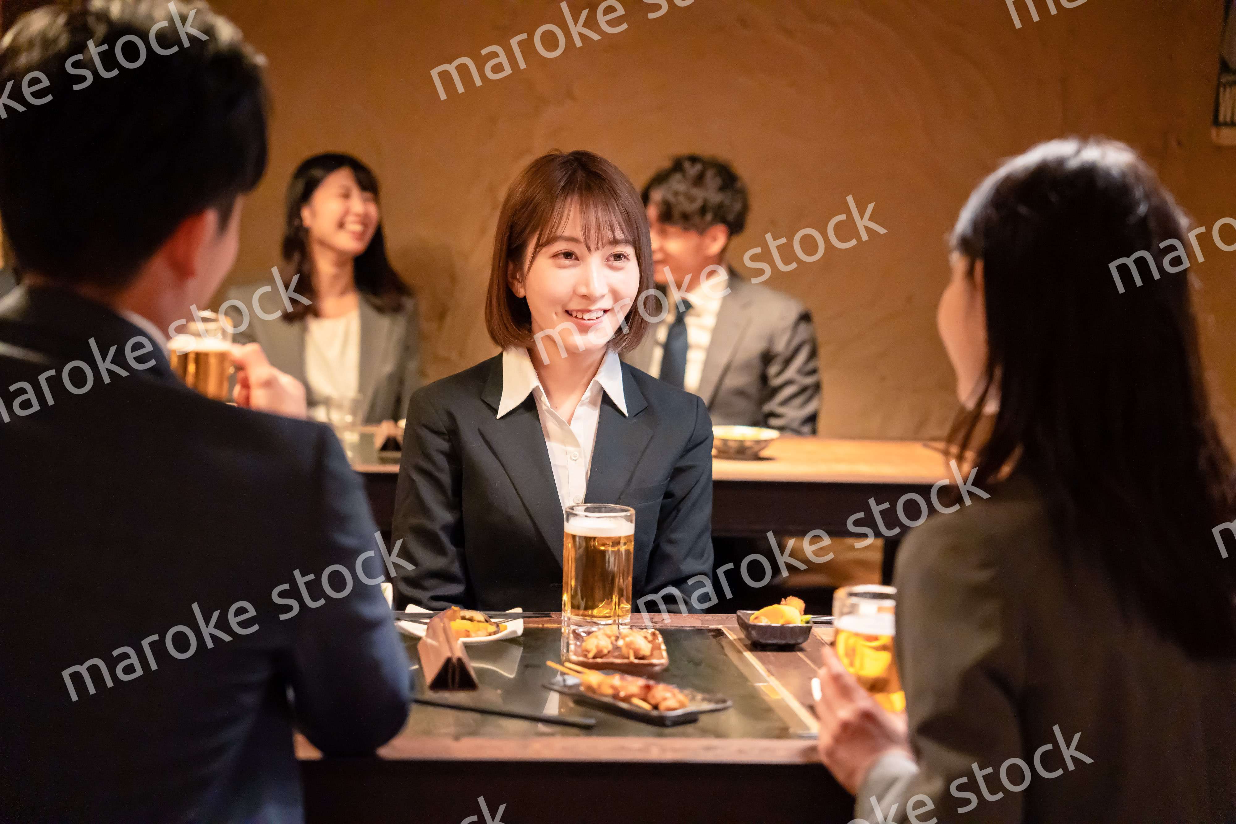 居酒屋で先輩社員とお酒を飲む新入社員