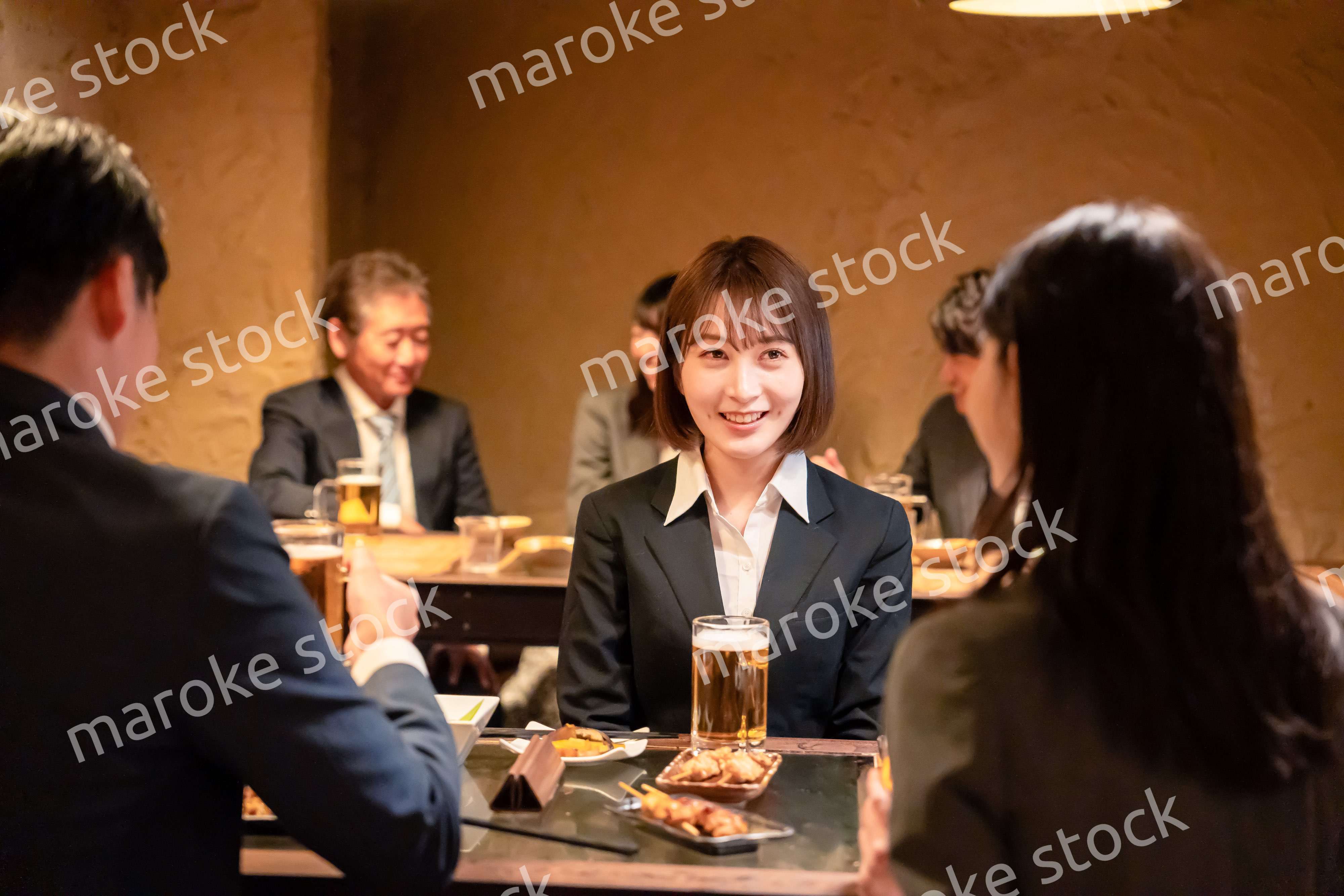 居酒屋で先輩社員とお酒を飲む新入社員