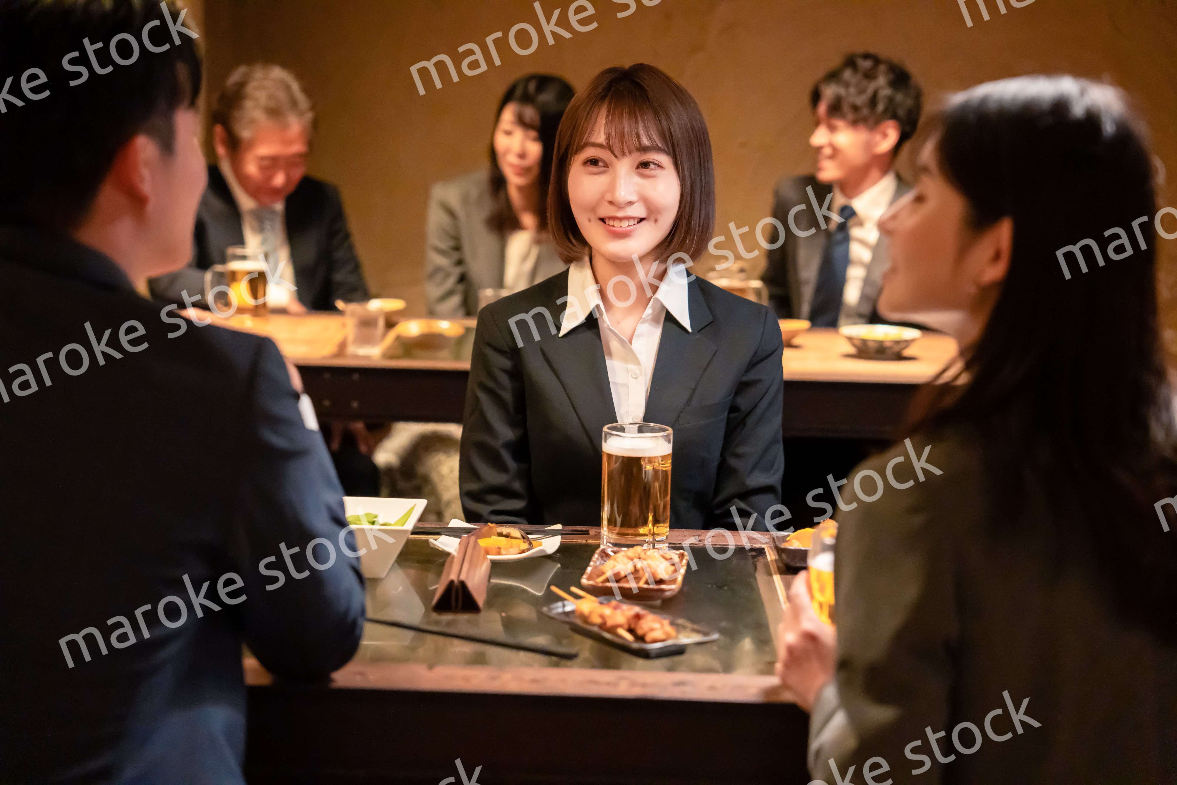 居酒屋で先輩社員とお酒を飲む新入社員