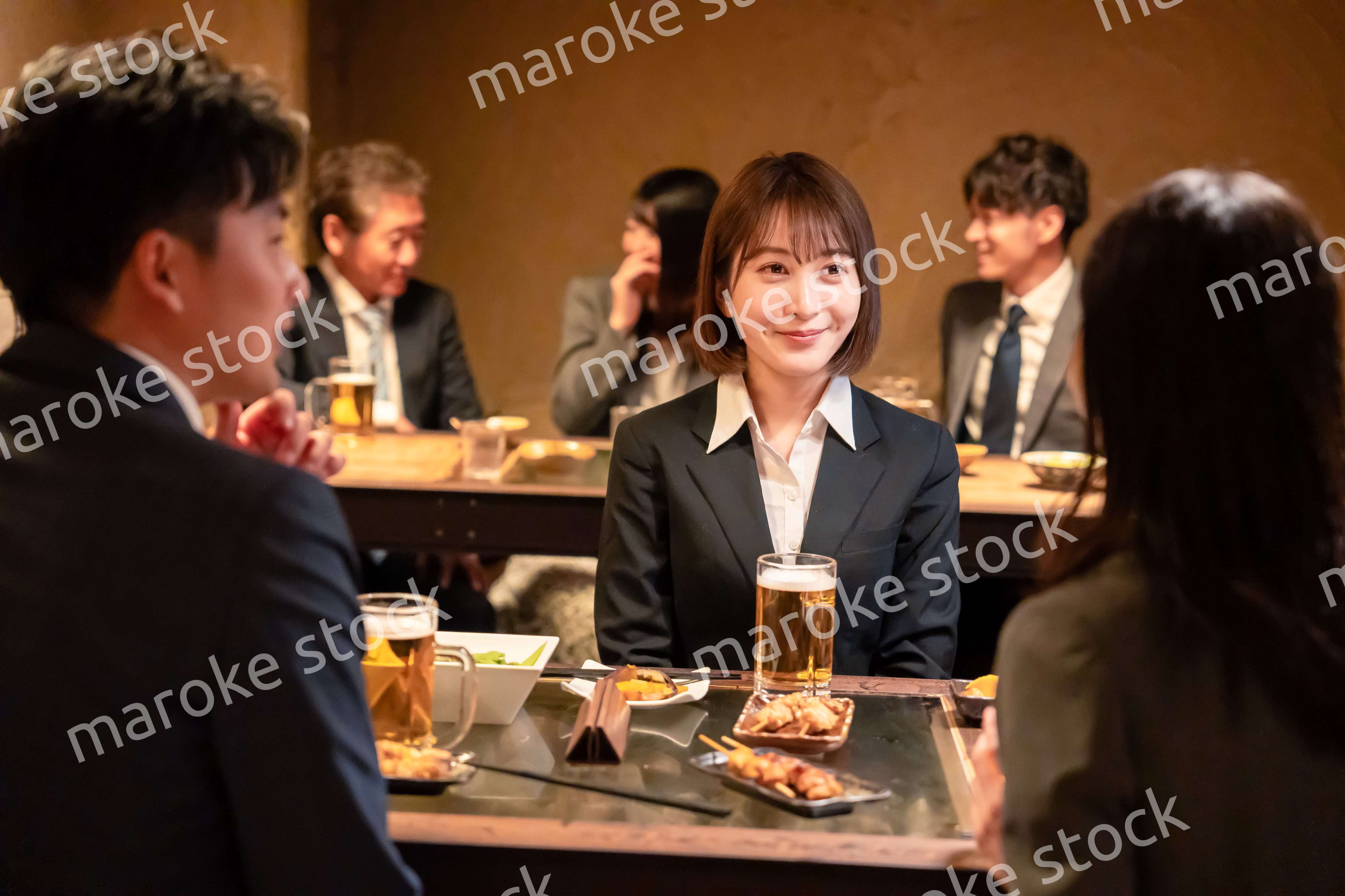 居酒屋で先輩社員とお酒を飲む新入社員