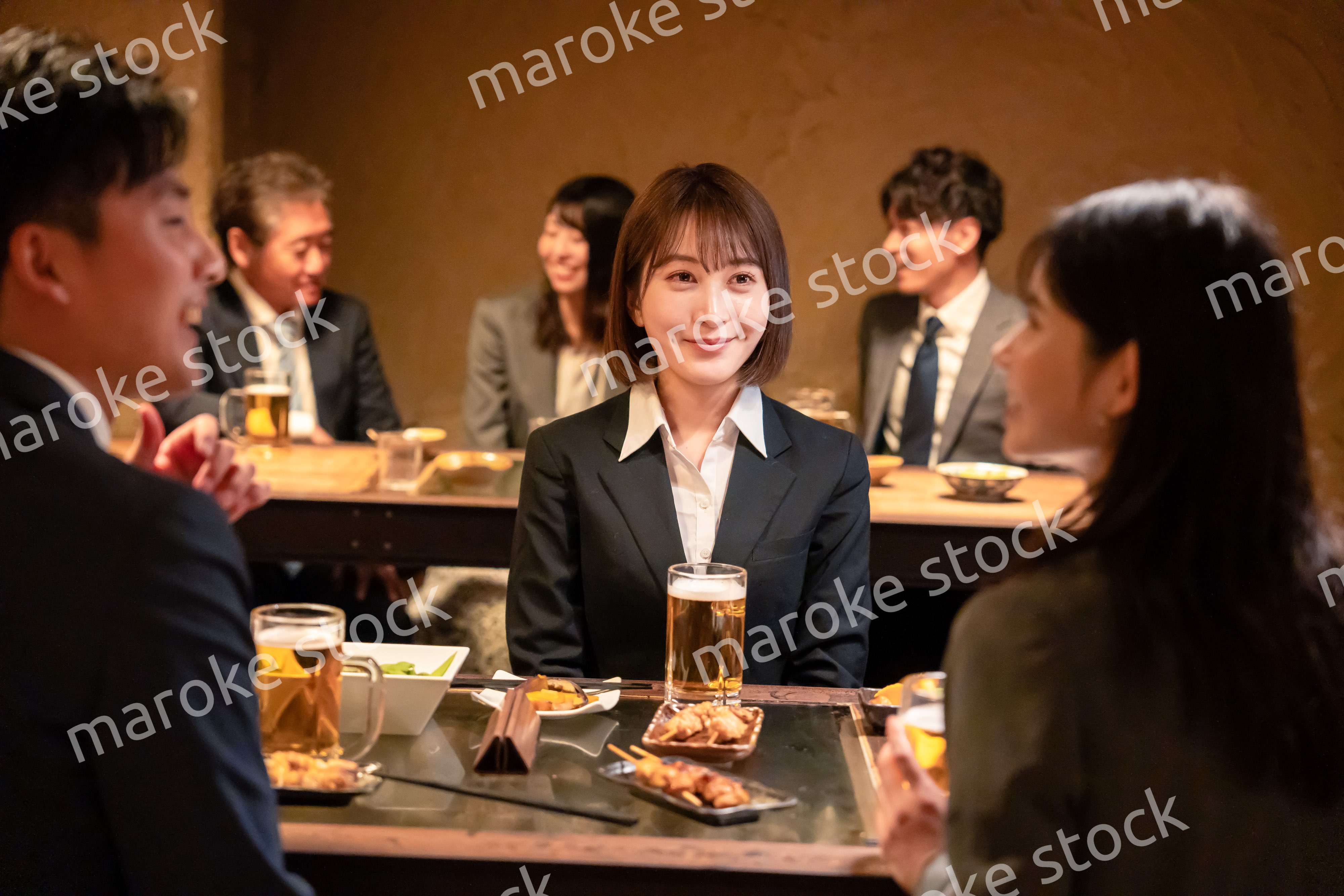 居酒屋で先輩社員とお酒を飲む新入社員